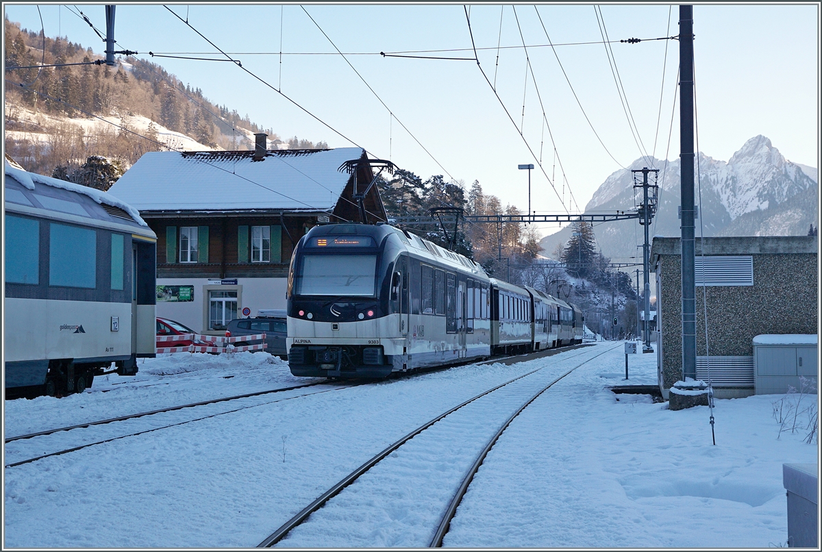 Am Schluss des GoldenPass Panoramic PE 2212 von Montreux nach Zweisimmen läuft der Alpina ABe 4/4 9303 mit. Der Zug ist hier beim halt in Rossinière zu sehen, links im Bild steht  eine MOB Panoramawagen auf einem Abstellgleis. 

11. Jan. 2021