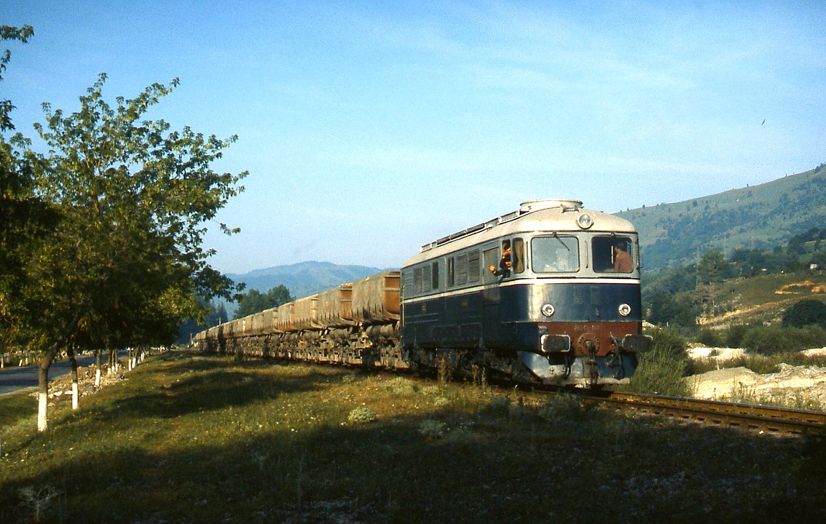 An einem Julimorgen 1992 ist eine der in Lizenz von SLM gebauten Electroputere-060 von Bicaz nach Piatra Neamt unterwegs. Das Lokpersonal grüßte die Fotografen am Wegesrand nicht optisch, sondern auch akustisch mit der Loksirene.