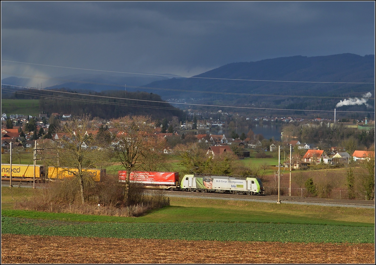 BLS Cargo bei Mumpf am Hochrhein. Die Fotowolke kann auch mal gnädig sein und durch den Regen den Blick in den Hotzenwald verschwommen erscheinen lassen. März 2017.