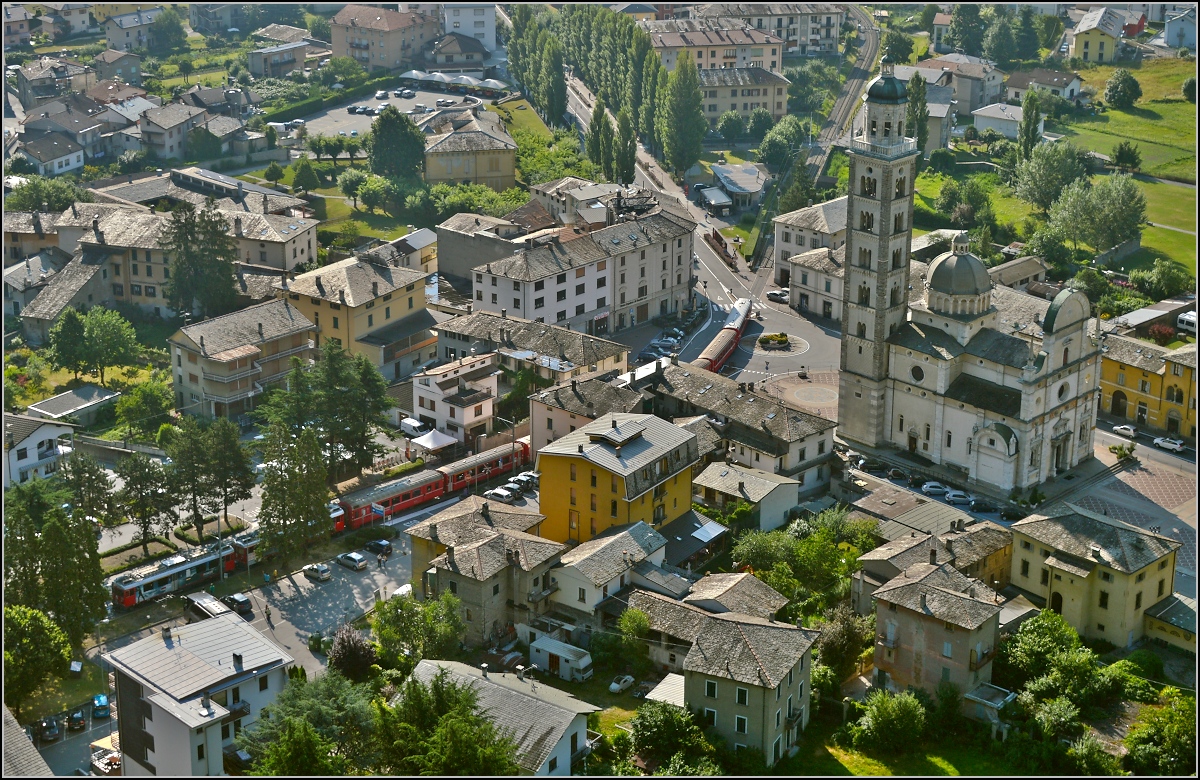 Der lange Zug von ABe 4/4<sup>III</sup> 55 Diavolezza und 56 Corviglia auf der Piazza Basilica in Tirano neben der Wallfahrtskirche Madonna di Tirano. Juli 2013.