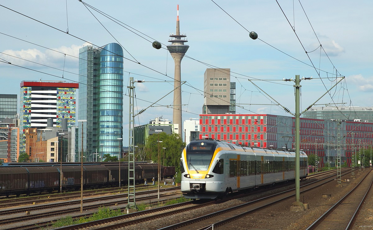 Der Stadler Flirt ET 7.01 der Eurobahn durchfhrt als RE 13 Hamm - Venlo/NL (Maas-Wupper-Express) am 25.05.2014 Dsseldorf-Hamm. Im Hintergrund die in den letzten Jahren enstandene Dsseldorfer Hafen-City, der der Triebwagen einen weiteren Farbtupfer hinzufgt.