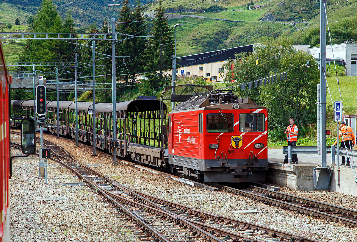 Die letzte, die Tunnellokomotive MGB Ge 4/4 III - 81 „Wallis“ der Matterhorn-Gotthard-Bahn ex FO MGB Ge 4/4 III - 81, steht am 07.09.2021mit einem Furka-Autoverladezug beim Bahnhof Realp (1.538 m ü. M.). 

Die Ge 4/4 III ist eine vierachsigen schmalspurige (1.000 mm) reine Adhäsions-Elektrolokomotive. Für die Beförderung der Autozüge durch den Furka-Basistunnel beschaffte die FO Furka-Oberalp-Bahn 1979 zwei vierachsige Schmalspurlokomotiven. Die Lokomotiven stellten eine Weiterentwicklung der RhB Ge 4/4 II der Rhätischen Bahn dar. Daher erhielten sie die Bezeichnung Ge 4/4 III, obwohl die FO keine weiteren Ge 4/4 besaß. Die Lokomotiven haben eine Leistung von 1.700 kW, eine Höchstgeschwindigkeit von 90 km/h und werden unter einer Fahrdrahtspannung von 11 kV, 16,7 Hz eingesetzt. Die Fahrzeuge sind die einzigen Streckenlokomotiven der MGB, die keinen Zahnradantrieb besitzen. Die MGB Ge 4/4 III - 81 „Wallis“ ist noch vorhanden, die Schwesterlok Ge 4/4 III - 82 „Uri“ wurde 2015 außer Betrieb gesetzt und als Ersatzteilspender für die 81 verwendet. Nachdem sie länger abgestellt war, erfolgte der Abbruch im November 2017. Einige Teile wurden für den Erhalt der Lok 81 eingelagert. Eines der beiden Urner Wappen von Lok 82 ist nun an einer Stirnseite der Schwesterlok 81 befestigt (wie hier im Bild zu sehen).

Die Lokomotive besitzt einen gesickten selbsttragenden Lokomotivkasten. Aus statischen Gründen musste die Einstiegstüre des Führerstandes nach hinten versetzt werden. Die Seitenwände haben keine Montageöffnung, sondern die ganze elektrische Innenausrüstung ist über die drei Dachluken eingebaut. Die Luftansaugöffnungen befinden sich auf dem Dach und sind für die Ausfilterung von Bremsstaub und feinem Flugschnee ausgelegt. Als Antrieb kam ein SLM-Schiebelagermotor zum Einsatz. Es handelt sich dabei um eine verbesserte Bauform eines Tatzlager-Antriebes, wobei sich der Motor eben auf kein festes, sondern ein seitenbewegliches Lager auf der Achse abstützt. Die beiden Schiebelager ermöglichen eine Axialverschiebung des Triebradsatzes. Somit wird der Radsatz in Querrichtung von der Masse des Motors entkoppelt. Die Schaltung des Hauptstromkreises entspricht weitgehend der RhB Ge 4/4 II, wobei im Traktionsstromrichter durch den technischen Fortschritt einige Vereinfachungen möglich waren. Auch in der Steuerung waren nur minimale Anpassungen erforderlich. Es ist deshalb auch möglich, mit der RhB Ge 4/4 II in Vielfachsteuerung zu verkehren
. 
Die Lokomotive besitzt für sich und die Autozug-Komposition eine Druckluftbremse. Diese ist mit einer Lufttrockungseinrichtung des Systems Lugart ausgerüstet, damit Bremsstörungen infolge der zum Teil doch harten Klimawechsel innerhalb und außerhalb des Tunnels vermieden werden können. Damit sie mit den übrigen Fahrzeugen verkehren kann, ist auch eine Vakuumbremse eingebaut. Als Handbremse bzw. Feststellbremse ist eine mit der Druckluft gekoppelte Federspeicherbremse eingebaut. 

TECHNISCHE DATEN:
Nummerierung: 	81, 82 
Spurweite: 1.000 mm (Meterspur)
Achsformel: Bo'Bo'
Hersteller: SLM Winterthur / 	BBC (technischer Teil)
Länge über Puffer: 12.900 mm
Höhe: 3.870 mm
Breite: 2.680 mm
Höchstgeschwindigkeit: 90 km/h
Dienstgewicht: 50 t
Stundenleistung: 1.700 kW
Treibraddurchmesser: 	1.070 mm (neu)
Anzahl der Motoren: 4
Steuerung:  Thyristor
Stromsystem: Einphasenwechselstrom 11.500 V / 16,7 Hz,

Geschichte:
Mit dem Bau des Furka-Basistunnels und dem Beschluss, ihn auch für den Autoverlad zu benutzen, war die Beschaffung der Autozugkompositionen zu evaluieren. Am Schluss blieb aus wirtschaftlichen Gründen eine konventionelle Lösung als Pendelzug mit einer Lok und Steuerwagen und dazwischen eingereihten Transportwagen. Als notwendige Transportkapazität wurden für Spitzenzeiten 100 Autos pro Stunde und Fahrrichtung angenommen, was zur Beschaffung zweier Kompositionen und damit dieser zwei Lokomotiven führte. 

Es wurden mehrere Varianten des Triebfahrzeugeinsatzes überprüft, darunter die Verwendung vorhandener Fahrzeuge mit und ohne Modernisierung. Dabei kam man zum Schluss, dass ein reines Adhäsionsfahrzeug der Bauart der RhB Ge 4/4 II die im Unterhalt kostengünstigste Lösung sei, wenn auch in der Anschaffung die teuerste Variante. 

Die FO ließ sich 1977 von der Industrie zwei Lokomotiven des Typs der RhB Ge 4/4 II offerieren, allerdings mit verstärkter elektrischer Bremse. Die Anbieter schlugen eine überarbeitete Lokomotive vor, die günstiger war, als die Ge 4/4 II vormals gekostet hatte. Die Änderungen gegenüber dem Referenzfahrzeug bezogen sich vor allem auf die Kastenbauform und den Antrieb. Die FO ging auf dieses Angebot ein. Zwischen der Ablieferung 1980 und der Inbetriebnahme des Furka-Basistunnels wurden die Lokomotiven an die RhB vermietet, die sie mit Schnellzügen auf der Albulalinie einsetzte. Seit 1982 werden sie ausschließlich für die Autozüge zwischen Oberwald VS und Realp UR verwendet. 

Eine Zugkomposition besteht aus:
An der Spitze des Zuges befindet sich immer auf der Seite Realp die Lokomotive. Es folgt ein Rampenwagen (Auffahrwagen) Sklv 4801 bis 4807, dann sechs Verladewagen (Sklv 4811 bis 4827), wieder ein Rampenwagen und als Abschluss ein Steuerwagen (BDt 4361bis 4363) auf der Seite Oberwald. Die Rampen- und Verladewagen sind mit Kuppelstangen fest zu einem Blockzug verbunden. Die Rampenwagen wiederum sind gegen die Lok und den Steuerwagen mit einer automatischen Kupplung +GF+, Typ Brünig, ausgerüstet.