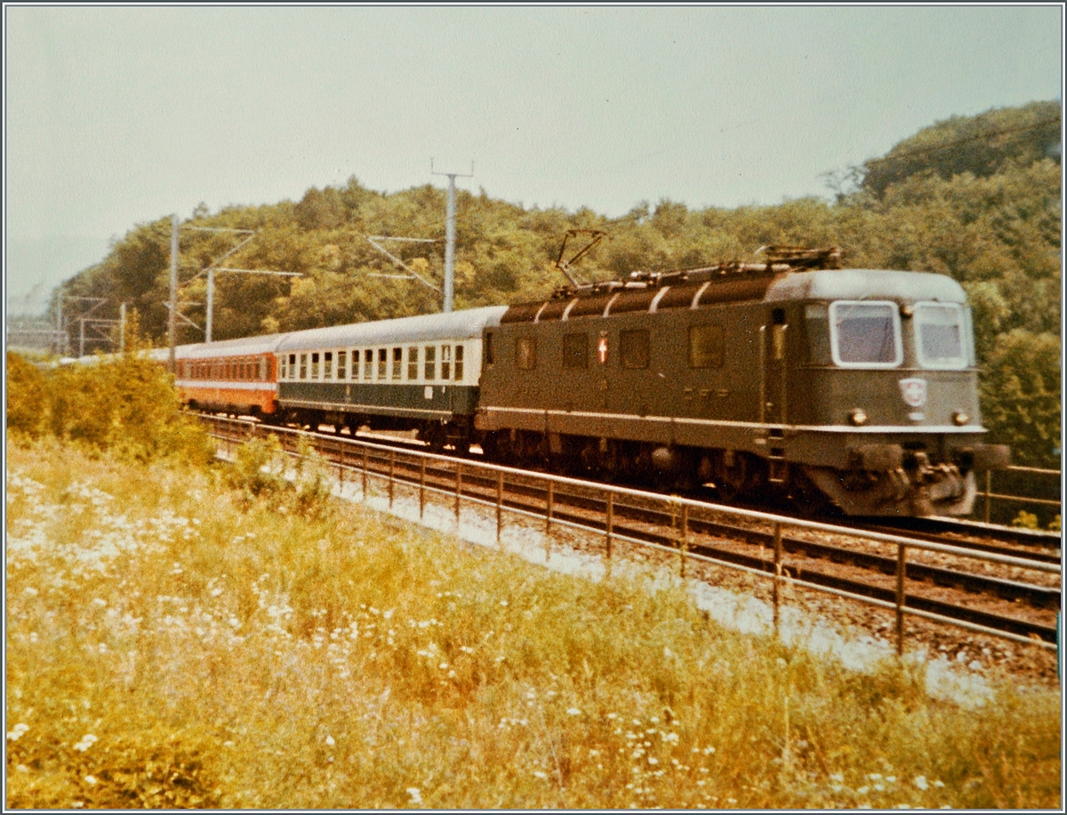Die SBB Re 6/6 11645  Colombier  ist mit dem IC 20383  Barbarossa  auf dem Weg in den Sden und infolge einer Betriebsstrung auf der Stammstrecke via Freiamt unterwegs und erreicht hier die Abzweigstation Gruemet, wo die Heitersberglinie auf die Strecke von Baden Oberstadt trifft. 

Analogbild vom 16. Juli 1982