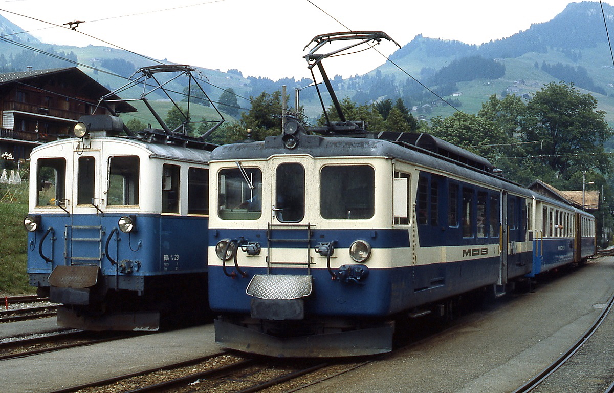 Im Juli 1983 begenen sich in Chateau d'Oex zwei Generationen: Der 1924 in Dienst gestellte BDe 4/4 28 vor einem Gterzug und einer der zwischen 1944 und 1946 gebauten BDe 4/4 3001-3006 mit einem Personenzug nach Montreux.