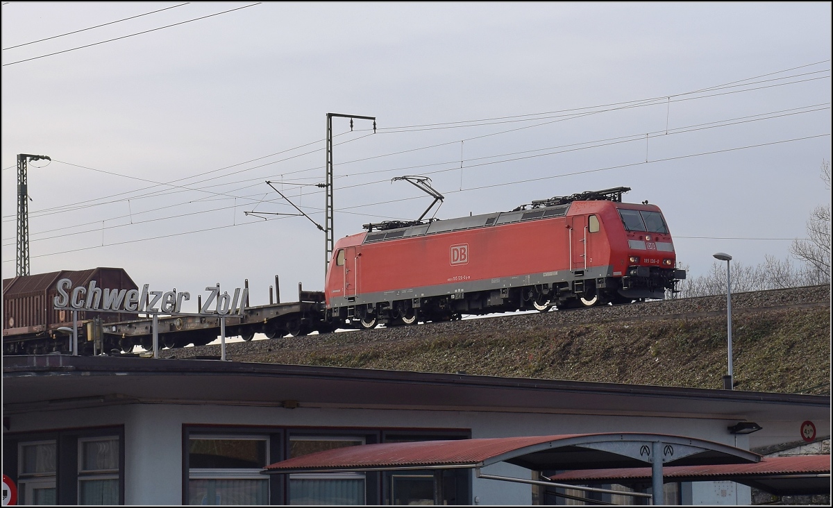 Kurz vor der Grenze nach Deutschland hat 185 126-0 noch schwer mit ihrem Güterzug zu kämpfen. Basel, Dezember 2017.