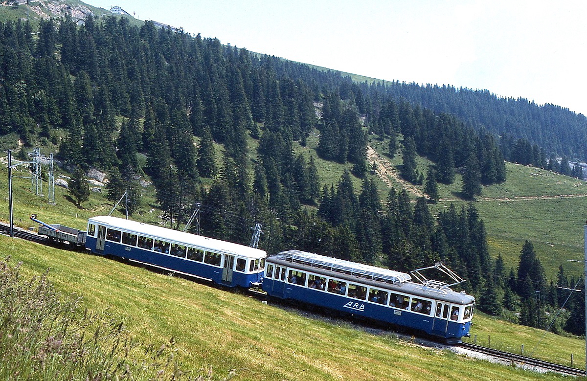 Kurz vor Rigi Staffel ist ein BDeh 2/4 der Arth-Rigi-Bahn im Juli 1983 unterwegs, oben links ist die Bergstation Rigi Kulm erkennbar. Wie man am Vorstellwagen erkennt, befindet sich unter den Fahrgästen auch ein Paraglider.
