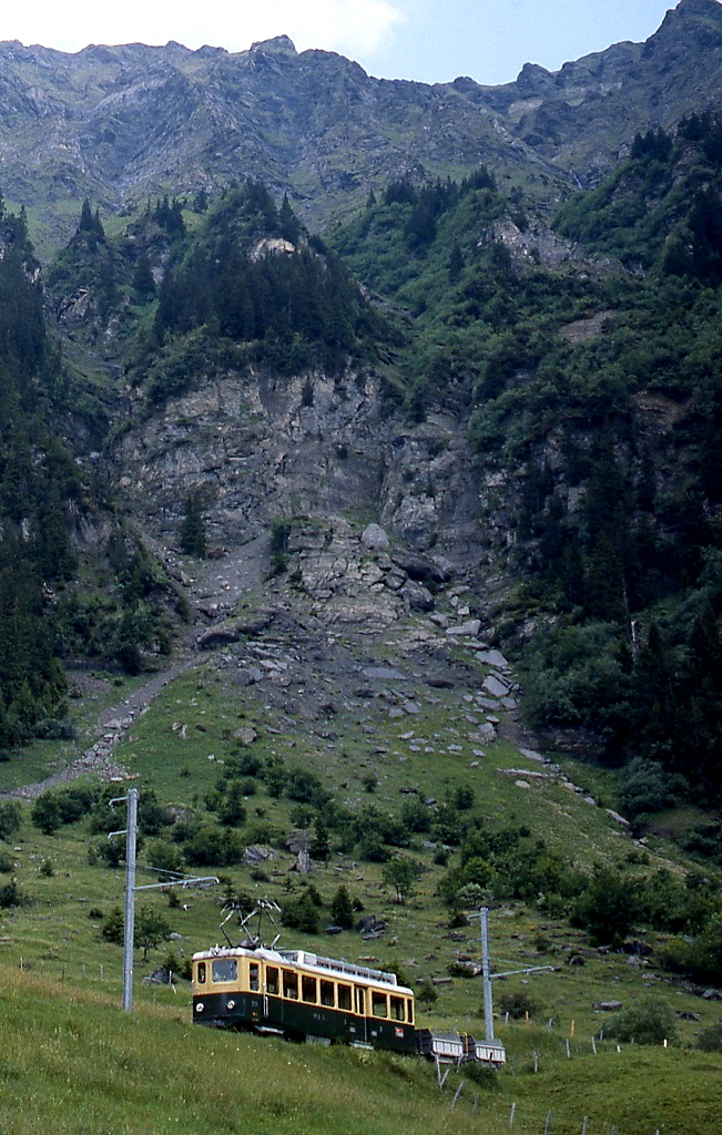 Mit einem Dienstzug ist ein BDeh 4/4 der Wengernalpbahn im Juni 1990 unterhalb der mächtigen Felswände des Lauberhorns unterwegs