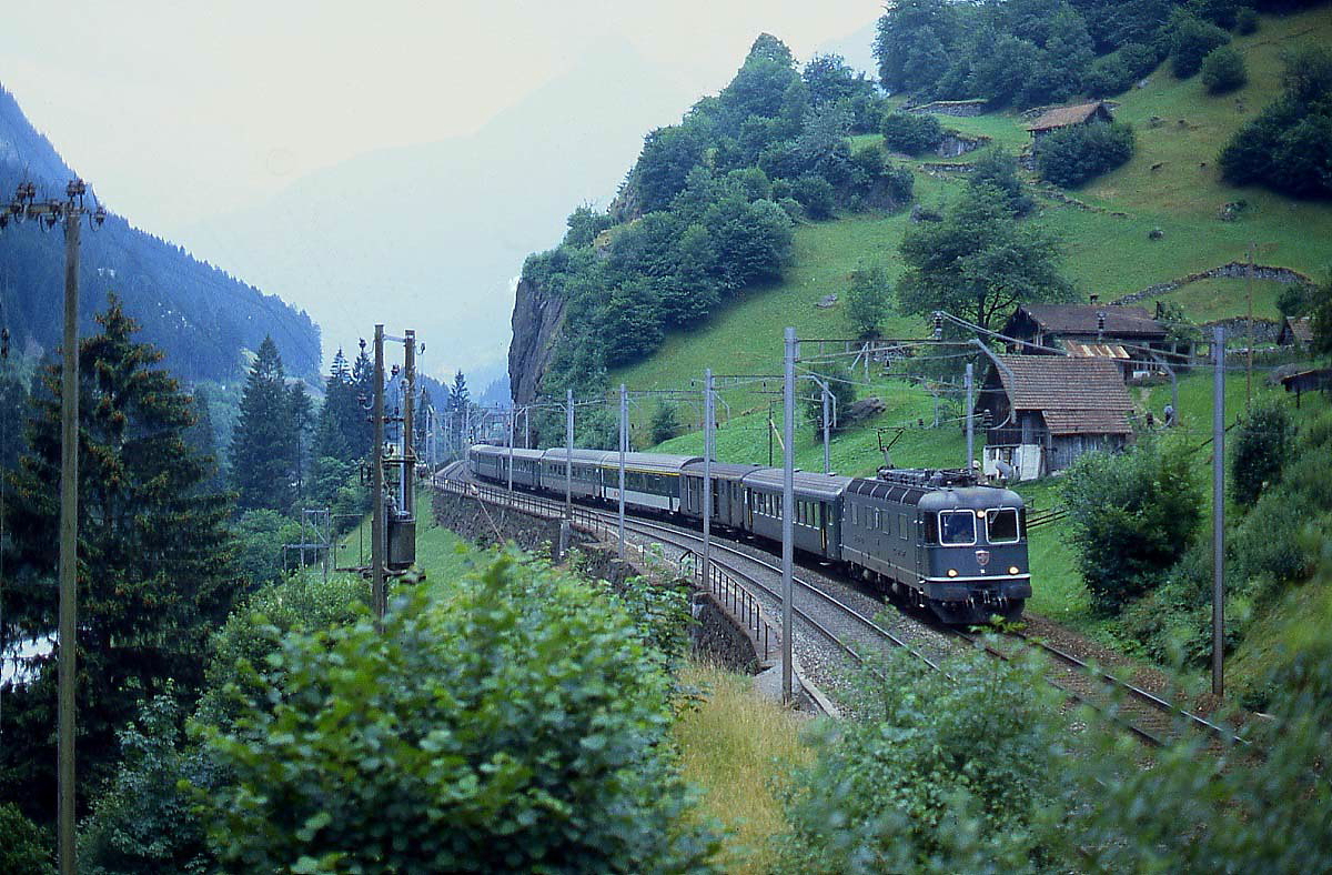 Mit einem Schnellzug wird eine Re 6/6 auf ihrer Fahrt Richtung Norden gleich in den Pfaffensprung-Kehrtunnel einfahren (Juli 1983)