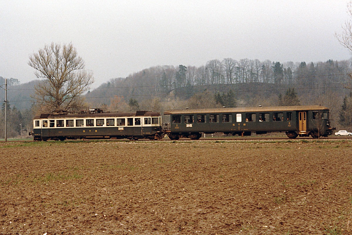 STB: Die Sensetalbahn hatte ihren Betrieb am 23.1.1904 aufgenommen. Die Streckenführung begann beim SBB-Bahnhof Flamatt und endete beim BN-Bahnhof Gümmenen. Am 23.5.1993 wurde der Streckenabschnitt Laupen-Gümmenen auf Busbetrieb umgestellt. Mit der Eröffnung der S-Bahn Bern wurde Laupen zu einem Endehalt einer S-Bahn. Die S-Bahn ab Freiburg endet bereits in Neuenegg. Zur Zeit befinden sich an der ehemaligen STB Strecke keine SBB Cargo Kunden mehr. Im Jahre 1986 wurden in Neuenegg die Güterwagen von einer SBB Ae 6/6 abgeholt. Ab dem Jahre 1987 hatte diese Aufgabe eine BLS Ae 6/8 übernommen. STB Pendelzug bestehend aus einem Be 4/4 106/107 ex SOB ABe 4/4 und dem Bti 201 ex BN Personenwagen auf dem Streckenabschnitt Laupen-Gümmenen im Jahre 1985.
Foto: Walter Ruetsch  