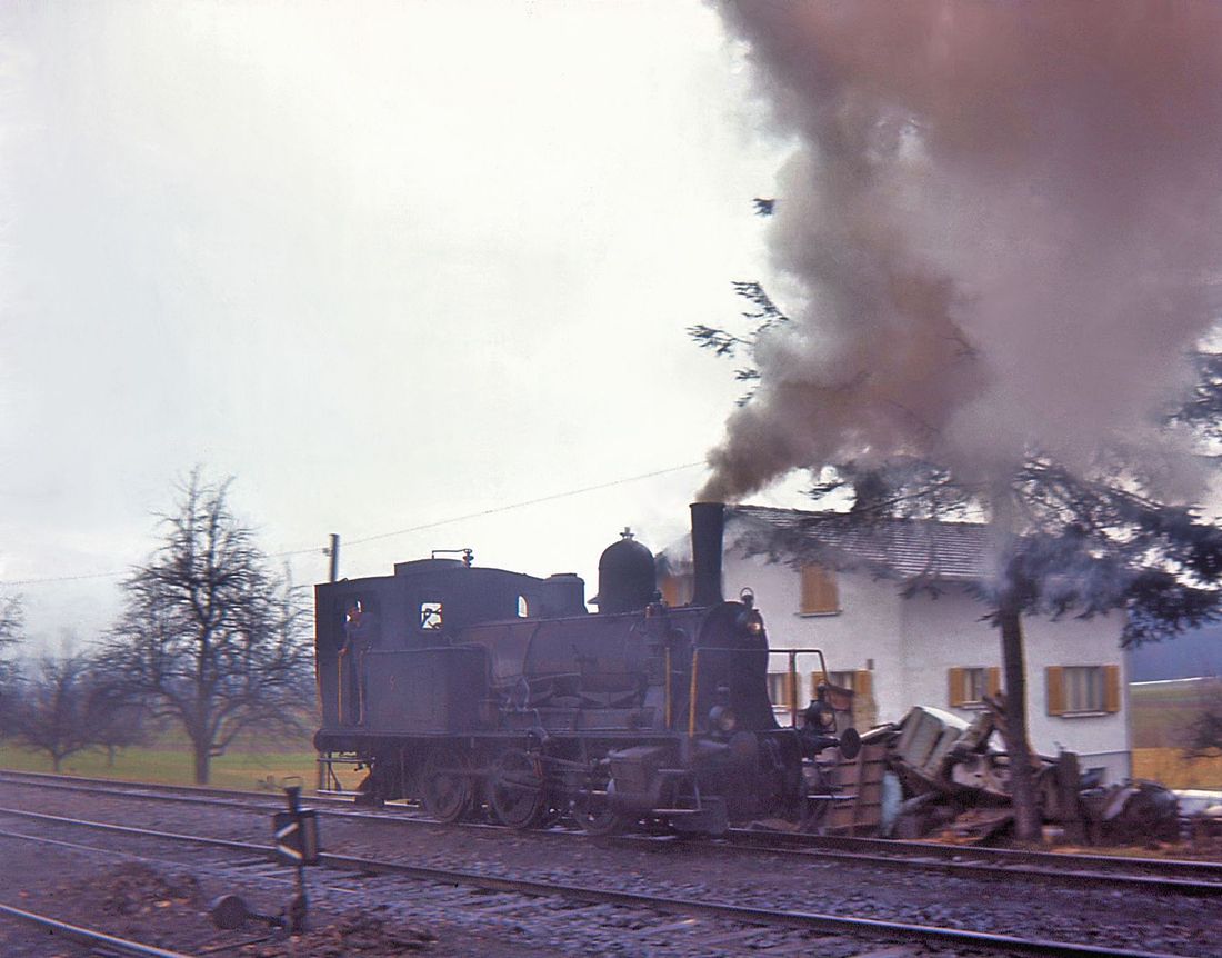 Sursee Triengen Bahn (Regelbetrieb): Der Rauch hüllt die Landschaft in einen diesigen bräunlichen Nebel. Triengen, 21.März 1965.  
