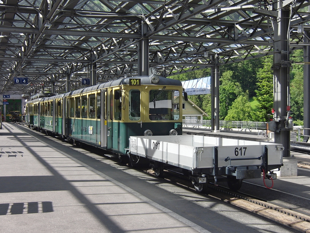 Unter dem vollständig überdachten Umsteigebereich zwischen Berner Oberlandbahn und Wengernalpbahn steht Triebwagen 101 der WAB mit vorgespanntem Gepäck-/Materialwagen am 15.06.2013 im Start-/Endbahnhof Lauterbrunnen.