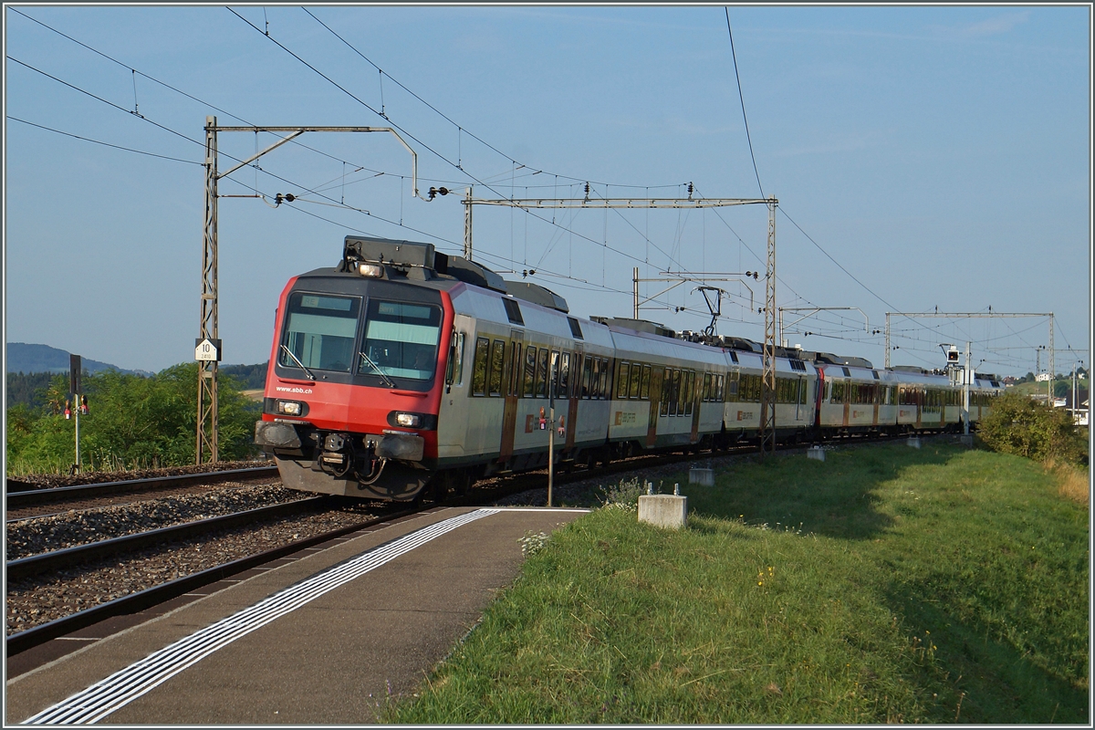 Zwei Domino Züge als RE Bulle/Palézieux - Bern auf dem Weg Richtung Fribourg erreichen noch unter der alten Fahrleitung den Halt Neyruz. 
6. Aug. 2015
