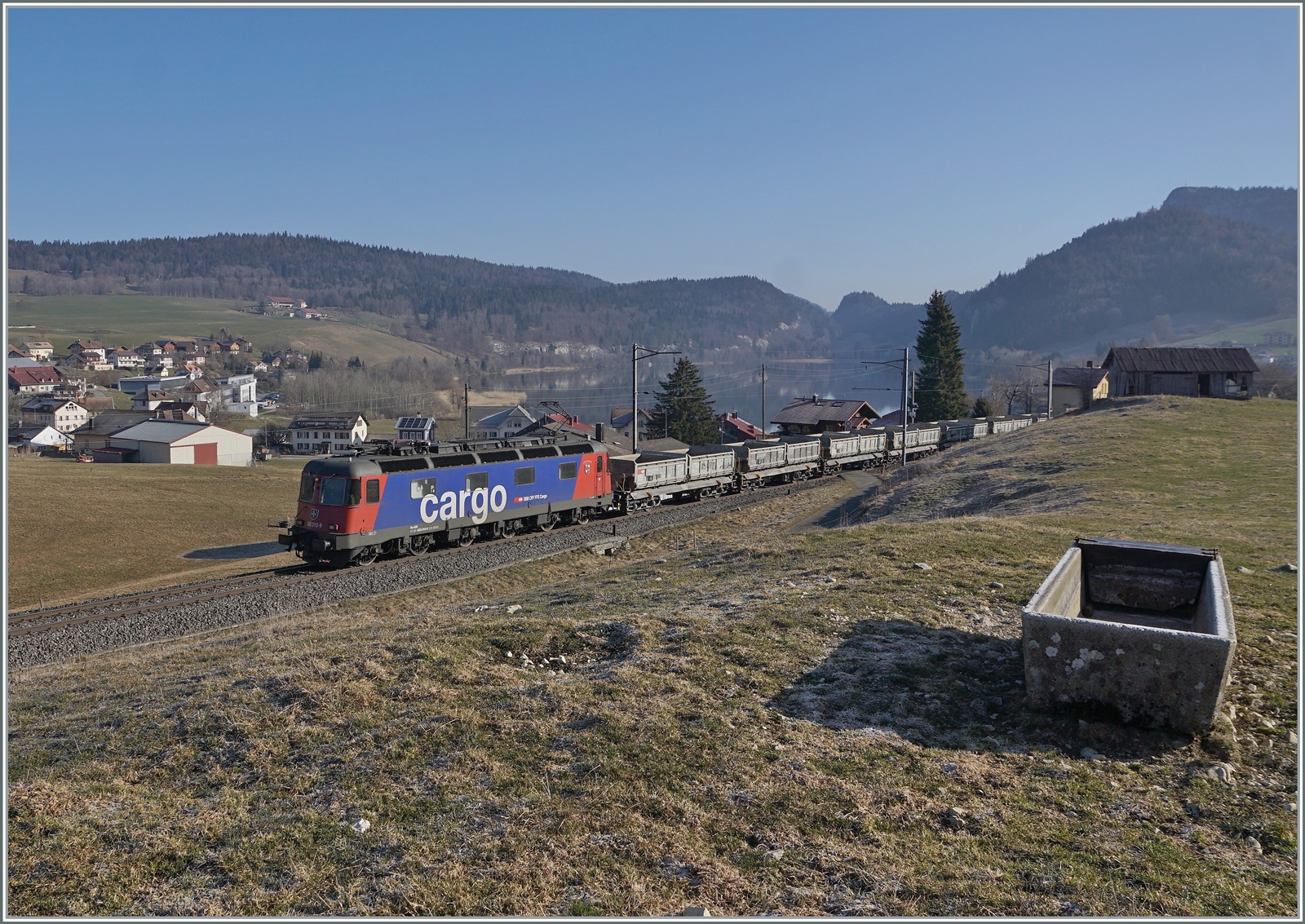 Für wenige Wochen verkehrte ein Güterzug mit einer Re 6/6 in Vallée de Joux - Die SBB Re 6/6 11610 (Re 620 010-9)  Spreitenbach  bringt etliche leere Fans-u Wagen als Güterzug 69701 von Lausanne-Triage nach Le Brassus und konnte hier bei Les Charbonnières mit dem Hintergrund des Lac de Brenet fotografiert werden.

24. März 2022