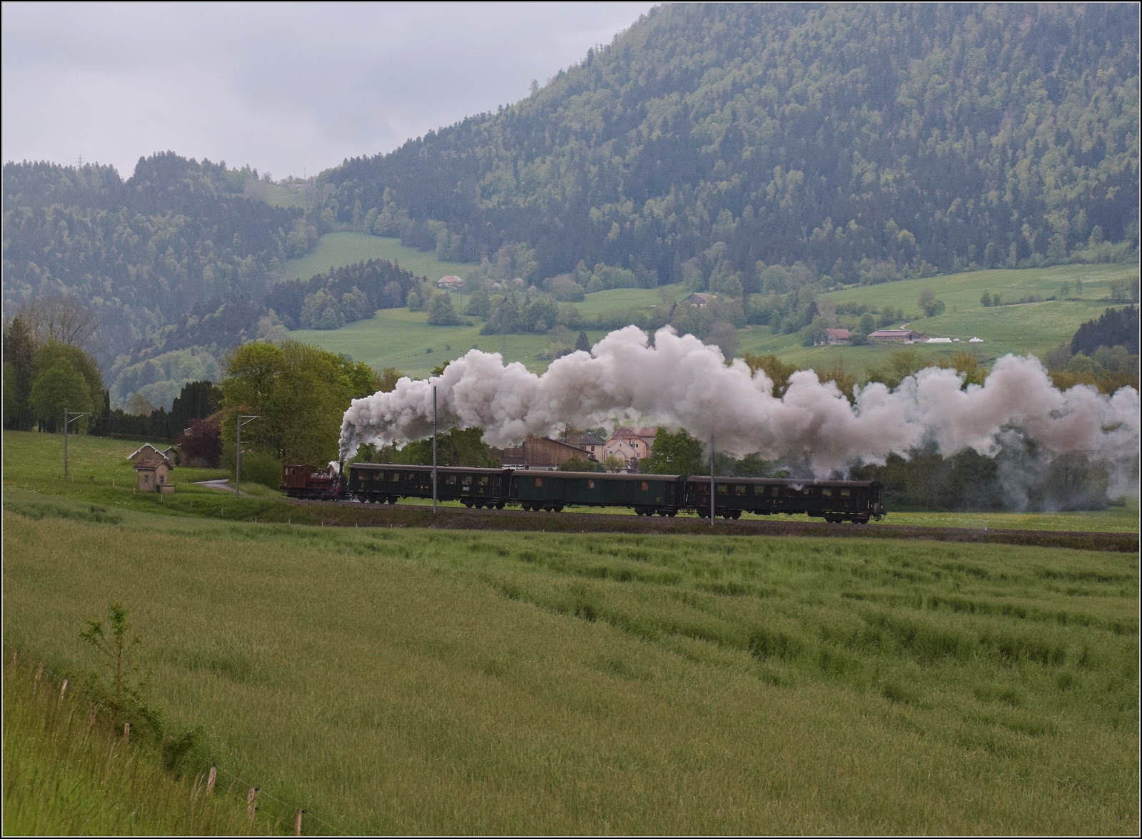 Vapeur Val-de-Travers: Train du Terroir.

E 3/3 8511 mit ihrem Zug in der Steigung von La Presta nach Travers. Mai 2023.
