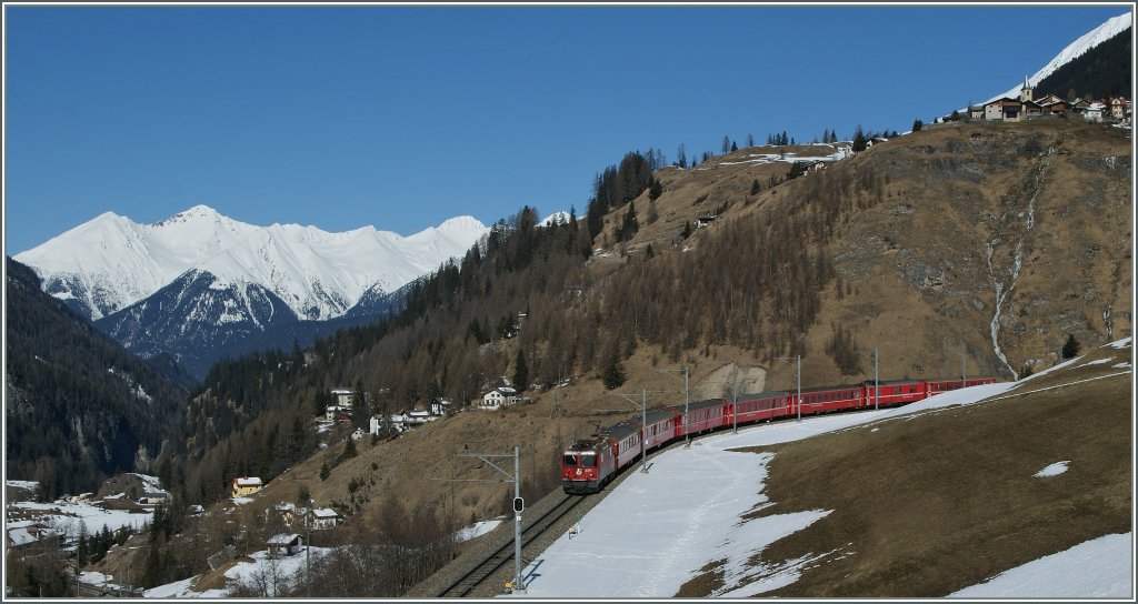 Die RhB Ge 4/4 II 429 mit dem Albulaschnellzug RE 1136 St. Moritz - Chur oberhalb von Bergn. Rechts oben im Bild der Ort Latsch, ganz unten rechts das Ablula Bahnmuseum welches sich gleich neben dem Bahnhof von Bergn/Bravuogn befindet. 16. Mrz 2013