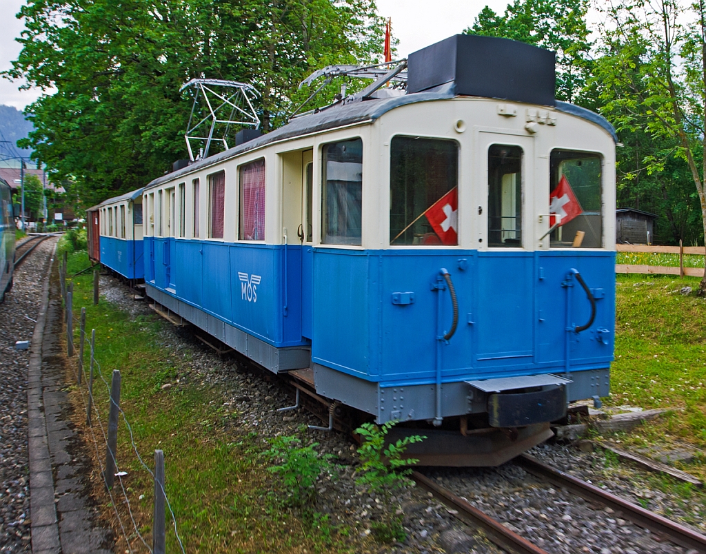 Ehemaliger MOB Triebzug De 4/4 26 mit B4 61 am 28.05.2012 in Saanen, aufgenommen aus fahrendem Zug. Der Zug ist seit 1994  abgestellt als der Vereinslokal odellbahngruppe Obersimmental-Saanenland (MOS). Der Triebwagen wurde 1912 SIG/Alioth als BFZe 4/4 26 gebaut, 1956 umgezeichnet in AFZe 4/4 26; 1962 in ADZe 4/4 26; 1971 in BDe 4/4 26; 1991 in De 4/4 26.