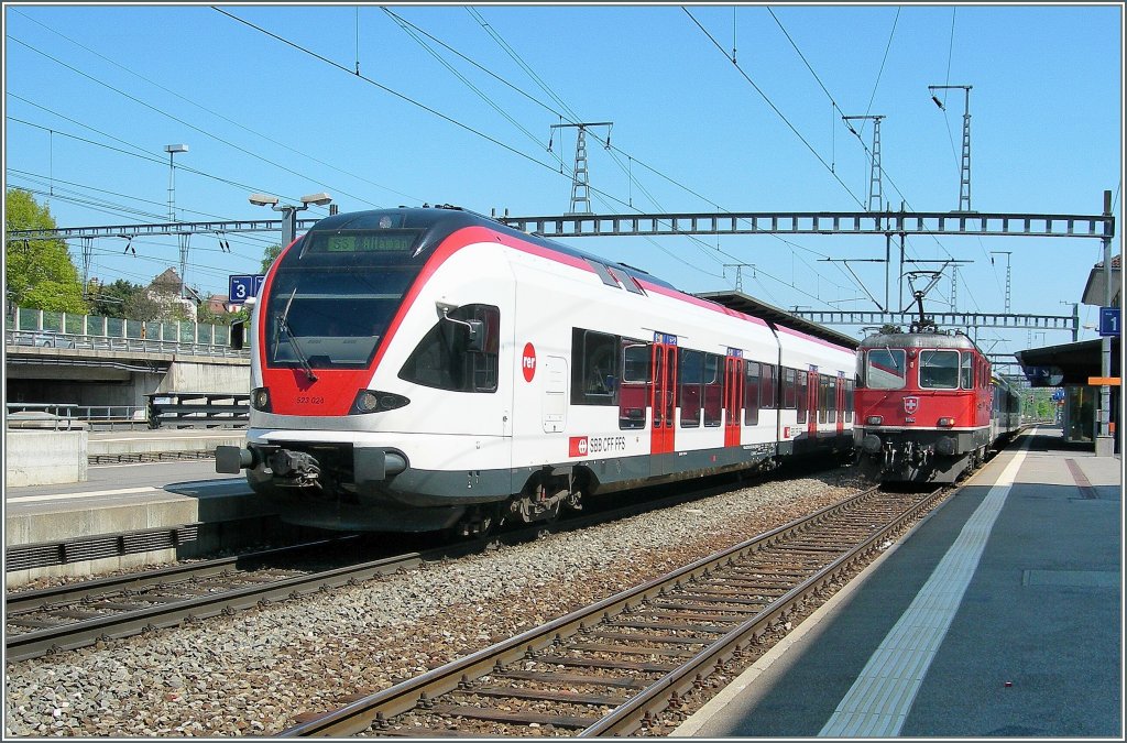 Ein SBB Flirt RABe 523 nach Allaman und im Hintergrund eine Re 4/4 II mit ihrem Regionalzug nach Palèzieux. 
Morges, den 19. April 2011