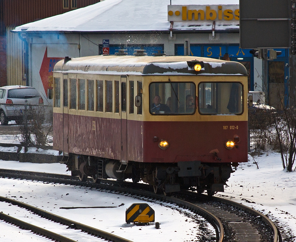 Ein Unikat mit einer sehr wechselhaften Geschichte, der Schmalspur (1.000 mm) Dieseltriebwagen 187 012 der HSB, ex T15 der MEG, ex WEG T35, ex VT3 der Langeooger Inselbahn, 
hier am 23.03.2013 als Zug-Nr. 8901 (morgendliche erste Zug; 7:45 Uht)  bei der Ausfahrt aus dem Bf Wernigerode nach Drei Annen Hohne.


Im Jahre 1955 wurde der heutige 187 012 von Waggonfabrik H. Fuchs, Heidelberg unter der Fabriknummer 9107, fr die Mittelbadische Eisenbahnen AG, gebaut. Er wurde auf der Strecke Zell -Todtnau (Frher Sddeutsche Eisenbahn Gesellschaft) als T15 der MEG eingesetzt. Die MEG war rechtlich ein Vorgnger der SWEG-Sdwestdeutschen Verkehrs-AG.

Dieser Triebwagen ist ein Unikat. 
An beiden Stirnseiten des Triebwagens gab es Tren fr den bergang zu den mitgefhrten Wagen. Das Fhrerpult fiel dementsprechend schmal aus. Die beiden Motoren wurden in Unterflurbauweise aus dem Wagenkasten verbannt, sodass ein sehr gerumiger Fahrgastraum entstand. Er wurde mit je zwei Faltgittertren an jeder Wagenseite gebaut. 

Leider wurde die 18 km lange Strecke Zell - Todtnau wegen Unwirtschaftlichkeit am 24. September 1967 geschlossen. Den T15 der MEG hat man zur Stammstrecke der MEG Bhl - Schwarzach verbracht. Doch fr diese Strecke erwies sich der T15 als vllig ungeeignet, denn er war einfach zu lang, fr die dortigen Bgen. 
Der MEG gelang es, einen Kunden fr den Triebwagen zu finden. Die Wrttembergische Eisenbahn Gesellschaft kaufte ihn 1968 fr ihre Schmalspurbahn auf der schwbischen Alb - der Strecke Amstetten   Laichingen. Hier wurde er nun zum T 35 der WEG. Bis 1972 kam er dort, jedoch nur selten, zum Einsatz. 
Er wurde umgebaut. Aus einer Stirnseite wurde die bergangstr entfernt und der Triebwagen behielt nur einen Motor - der zweite Motor wurde entfernt. Der WEG T35 blieb auch nach dem Umbau ein Reservefahrzeug, weil er auf dieser Bahn nicht fr den Gterverkehr eingesetzt werden konnte. 
Die WEG sah sich nun ihrerseits nach einem weiteren Kufer fr den T35 um und verkaufte ihn 1976 an die Langeooger Inselbahn. 
Doch bevor der sddeutsche Triebwagen zum  Insulaner  wurde, arbeitet man ihn in der Bremer Waggonbau GmbH grndlich auf. Er erhielt zwei neue Motoren Bssing (Braunschweig) U11 D mit je 155 kW (210 PS).  Das mechanische RENK-Getriebe wurde durch zwei hydromechanische Differentialwandler-Getriebe vom Typ VOITH 501 (Bauart 380 U+S 320) ersetzt. Die noch verbliebene bergangstr an der Frontseite wurde zudem auch entfernt. Auf einer Wagenseite wurden die Falttren ausgebaut. 

Auf Langeoog wurde er zum T3 und fuhr im Juni 1976 erstmalig ber die Insel. Dort verrichtete er viele Jahre klaglos seinen  windigen  Dienst. Aber es sollte nicht die letzte Etappe seiner Odyssee durch Deutschland gewesen sein. 
Am 13. April 1995 unterzeichneten die HSB den Kaufvertrag fr drei Triebwagen der Langeooger Inselbahn - darunter den des T3 (Langeoog). 
Den Weg in den Harz legte der angehende 187 012 auf einem Tieflader bis Halberstadt und von dort per Schiene im Mai 1995 zurck. Fr seinen Einsatz im Harz waren jedoch erneut einige Umbauten erforderlich. Besonders wichtig hierbei war die Wiedereinrichtung von Tren auf beiden Wagenseiten, da sich die Bahnsteige der HSB sowohl rechts als auch links in Fahrtrichtung befinden. Im Zuge dieser Manahme wurden die alten Falttren entfernt und durch Tren neuerer Bauart ersetzt. 
Der 187 012 wird heute vorwiegend im ffentlichen Personennahverkehr zwischen Nordhausen und Ilfeld (Harzquerbahn), sowie zwischen Wernigerode nach Drei Annen Hohne (Brockenbahn) eingesetzt.


Technische Daten:
Hersteller: Waggonfabrik H. Fuchs, Heidelberg
Fabriknummer: 9107
Spurweite: 1.000 mm 
Achsanordnung: B' B' dh (Original B' B' dm) 
Lnge ber Puffer: 16.130 mm
Fahrzeughhe: 3.360 mm 
Achsabstand im Drehgestell: 1.860 mm
Drehzapfenabstand: 11.700 mm
Leergewicht: 23,3 t 
kleinster befahrbarer Gleisbogen: 50m
Hchstgeschwindigkeit: 60km/h
Sitzpltze: 48
Stehpltze: 40

Motor/Leistung: 
2 Stck Bssing 6-Zylinder-Unterflur-4Takt-Diesel mit Direkteinspritzung.
Typ:U11 D/210 
Leistung: je 155 kW (210 PS) bei 2.100 U/min
Hubraum:11.581 cm3
Zylinderanordnung: Reihe, liegend
Khlung: Wassergekhlt
(Original 2 Motoren  132 kW bzw. 180 PS)

Getriebe: Voith Differentialwandlergetriebe (hydrodynamisch) Typ 501 Bauart 380 U+S 320

Bei diesem dieselhydraulischen Triebwagen hat jedes Drehgestell  seine eigene Antriebsanlage, Dieselmotor in Unterflurbauweise und hydrodynamisches Getriebe.
