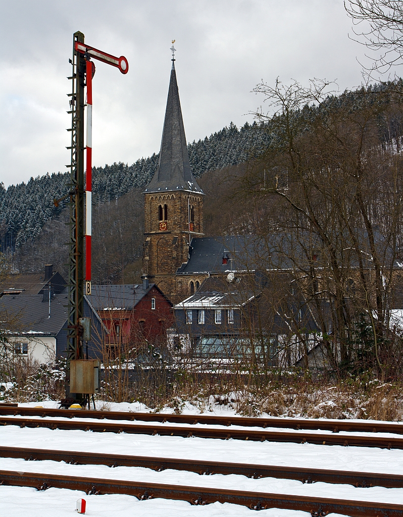 Einflgeliges Form-Hauptsignal (hier auf Hp 0 „Halt!“) als Ausfahrtsignal  (in Richtung Betzdorf) am Gleis 1 vom Bahnhof Herdorf (09.02.2013). 

Unten links am Bildrand das Signal Ra 12 / So 12 (Grenzzeichen), dies zeigt die Grenze an , bis zu der Fahrzeuge bei Weichenverbindungen profilfrei abgestellt werden drfen.
Bei Weichenverbindungen, an der ja zwei Gleise zusammenlaufen, berhren sich die Lichtraumbereiche beider Gleise. Der Punkt, an dem sie sich gerade berhren, ist dieses Zeichen gekennzeichnet. Bis zu diesem Zeichen drfen Fahrzeuge abgestellt werden, ohne da Fahrzeugbewegungen im Nachbargleis behindert werden.

Im Hintergrund die katholische Kirche St. Aloisius.
