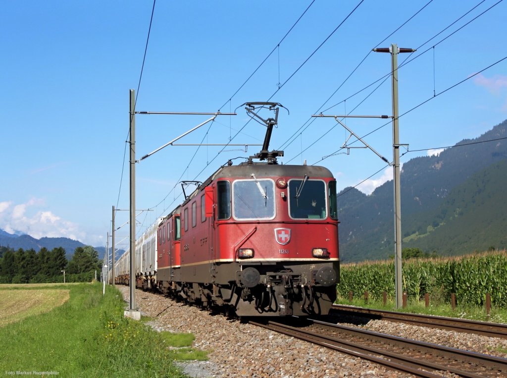 Re 4/4 II 11241 mit einer Schwesterlok mit einem Holzschnitzel-Zug ber das Dreischienengleis am 04.08.10 bei Felsberg