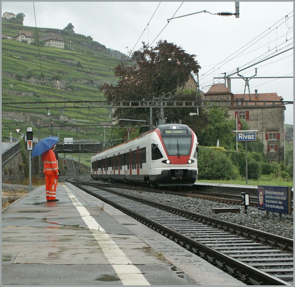 Regen: Pfützen und Schirm zeigen: es regnet, als der SBB Flirt RABe 523 am 16. August 2010 Rivaz erreicht. 