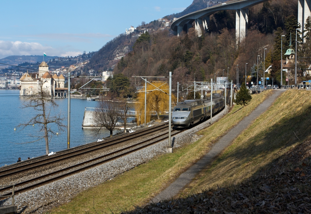 TGV Lyria (112) der Verbindung Paris–Dijon–Lausanne–Brig bediehnt, er fhrt hier am 26.02.2012 bei  Clos du Moulin am Genfersee Richtung Brig entlang, hinten Chteau de Chillon, dahinter Montreux.