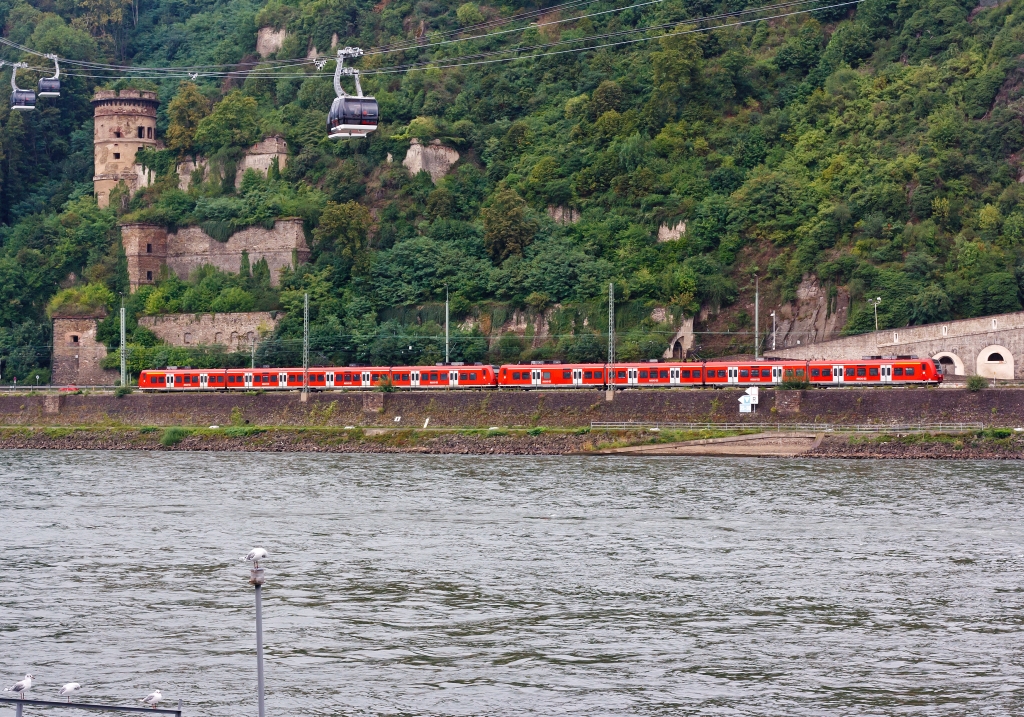 Zwei gekuppelte 425er-Triebzge als RE 8 (Rhein-Erft-Express) hat am 13.08.2011 den Bf Koblenz-Ehrenbreitstein verlassen und fhrt in Richtung Kln und Mnchengladbach. Darber ist die Rheinseilbahn in Koblenz zusehen.
