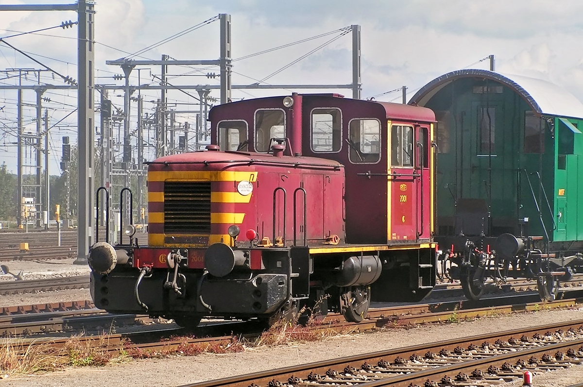 . Am 19.09.2004 rangierte die ex CFL 2001 die Museumsbahnwagen im verrauchten Bahnhof von Ptange. (Hans)

Diese Lok ist ein Kuriosum und kann deshalb in keine der Kategorien fr luxemburgische Dieselloks einsortiert werden.

Die 2001 ist eine Deutz Lok vom Typ A 12 L 614. usserlich hnelt sie den Loks der Srie 1020, aber whrend diese ber ein Nachschaltgetriebe durch Triplex-Rollenketten angetrieben werden, erfolgt dies bei der 2001 ber Kuppelstangen und einer zwischen den Achsen angeordneten Blindwelle.

Unter der Nummer 2001 kam sie vorerst als Werkslok zum Betriebswerk Luxemburg. Warum die aus dem Rahmen fallende Nummer 2001 gewhlt wurde, ist nicht berliefert. Normal wre de Nummer 1031 gewesen.

Nachdem die Lok 1988 bei der CFL ausgemustert wurde, kam sie im Frhjahr 2001 zur Museumsbahn Train 1900 nach Fond de Gras.

Die technischen Daten der 2001:

Baujahr: 1957
Baunummer: 56764
Spurweite: 1435 mm
Dienstgewicht: 28 t
Leergewicht: 27 t
Achsdruck: 14 t
Achsstand: 2650 mm
Laufkreisdurchmesser der Rder: 850 mm
Kleinst befahrbarer Kurvenradius: 60 m

