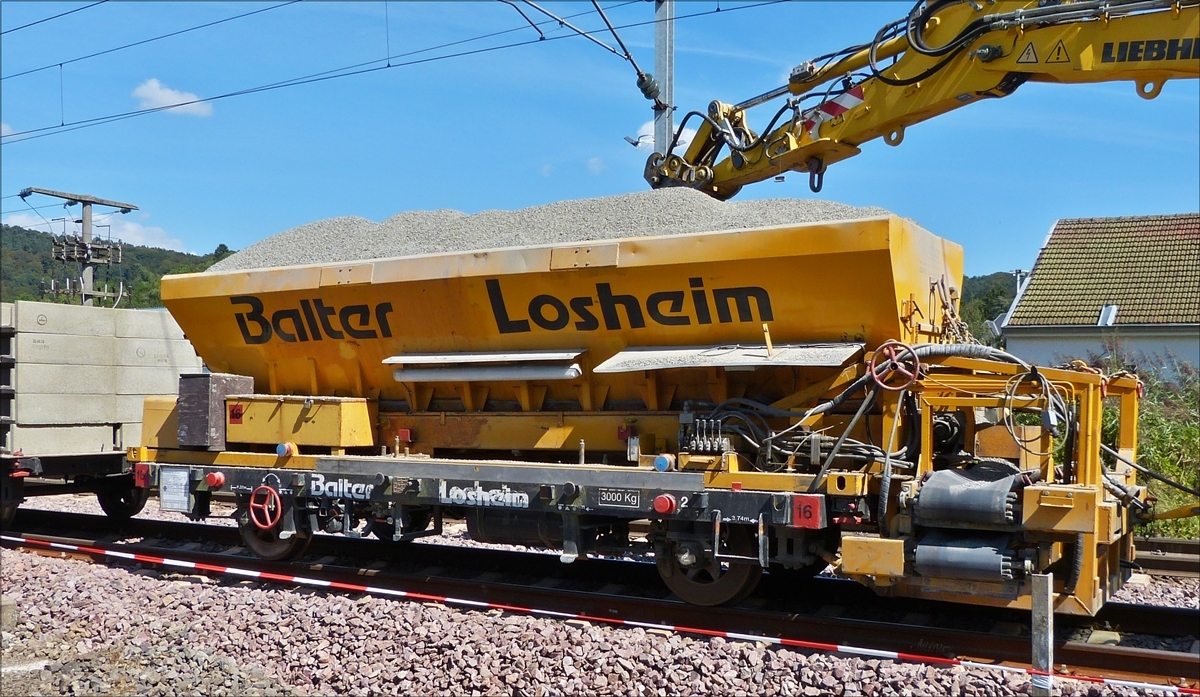 . Auf einem 2 achsigen Kleinwagen der Art Gleiskraftwagen, steht ein Silo beladen mit feinem Kies welcher per Förderband an den Rand des Bahndammes verteilt wird. Er wurde soeben an der Verladestelle nahe Lintgen neu beladen.  September 2016