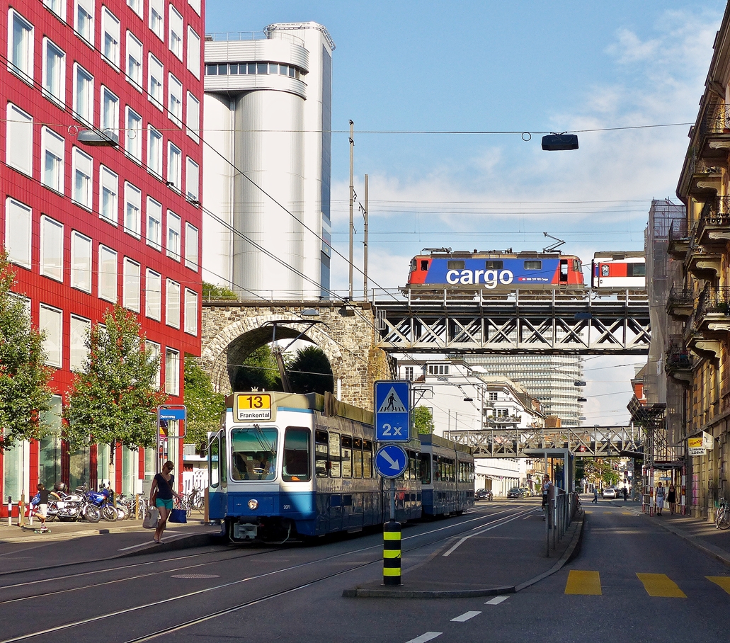 . Die VBZ Tram 2000 (Be 4/6) N 2071 steht am 05.06.2015 an der Haltestelle Dammweg in der Limmatstrasse in Zrich, whrend eine SBB Cargo Re 421 mit ihrem Zug ber den Viadukt fhrt. Wahrscheinlich handelt es sich um den EC 197 Zrich HB - Mnschen Hbf via Lindau Hbf. (Jeanny)