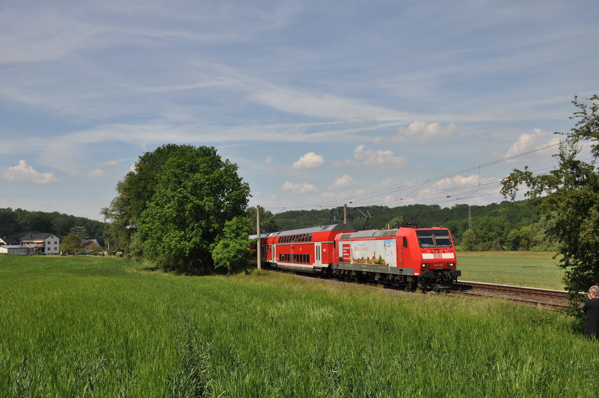 146 127  Marienhafe  ist hier auf ihrer ersten Fahrt für DB Regio Hessen am 11.06.2021 in Lindenholzhausen zu sehen, sie ist als RB22 nach Frankfurt Hbf unterwegs.
Die Lok wurde kurzfristig eingesetzt, da 146 126 an diesem Tag eine Störung hatte und abgeschleppt werden musste. Eine 143 wollte man wohl nicht mehr in dem Umlauf schicken.
Vielleicht überlegte sich ja der ein oder andere Fahrgast bei Anblick der Lok den Erholungsort  Marienhafe  mal aufzusuchen. :-) 