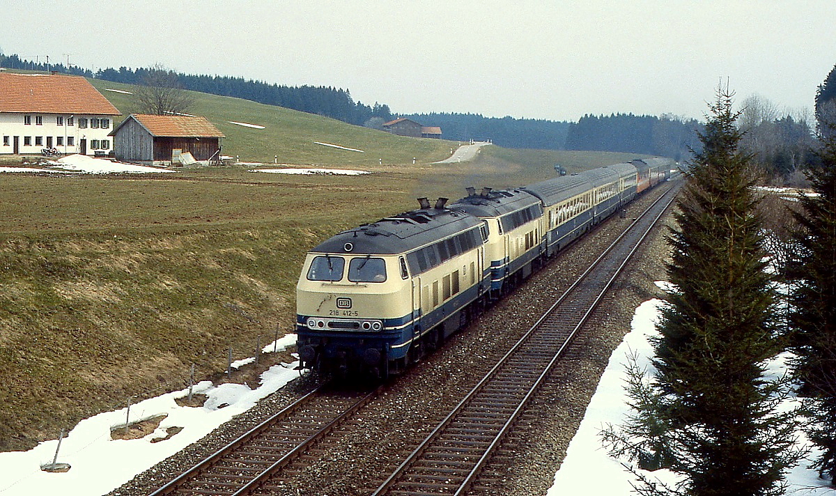 218 412-5 und eine weitere 218 sind Anfang April 1988 mit einem Schnellzug bei Günzach auf der Allgäubahn in Richtung Schweiz unterwegs