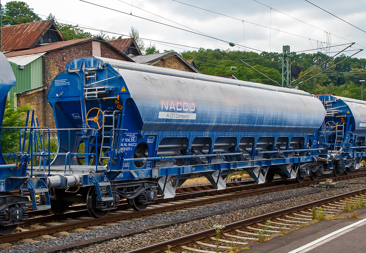 4-achsiger Trichtermittenentladewagen 82,5 m³ der Gattung Tadns (Drehgestell-Schüttgutwagen mit Schwenkdach) beladen mit Kalk, 37 84 0839 009-4 NL- NACCO, der NACCO GmbH, am 07.07.2019 im Zugverbund bei einer Zugdurchfahrt in Betzdorf (Sieg). Seit August 2018 gehören diese Wagen der WASCOSA AG und wurden später umgezeichnet. 

Der mit einer hohen bilateral kontrollierten Schwerkraftentladung und einem zu öffnenden Dach ausgestattete Wagen ist für den Transport von Kalksteinen und anderen Schüttgütern, die vor Witterungseinflüssen geschützt werden müssen, konzipiert worden. Das Schüttgut wird mit Hilfe der Schwerkraft über die Dachöffnung eingefüllt. Das kontrollierte Entladen wird manuell durchgeführt. Die Entleereinrichtung besteht aus 4 Auslauftrichtern die mit je 2 Klappen verschlossen sind und manuell per Hebel, einzeln von den beiden Plattformen an den Wagenenden aus betätigt werden. Die Komplette Entladung des Wagens ist durch Öffnung auf nur einer Seite möglich. Die Entladung des Wagens erfolgt auf Förderbändern oder in unterirdische Bunker.

TECHNISCHE DATEN:
Hersteller: Astra Rail Industries (Rumänien) gehört zu Greenbrier Europe
Spurweite: 1.435 mm
Ladeprofil: G1-TSI
Länge über Puffer : 19.040 mm
Drehzapfenabstand: 14.000 mm
Achsabstand im Drehgestell: 1.800 mm
Eigengewicht: 24.750 kg
Höchstgeschwindigkeit: 100 km/h (beladen) / 120 km/h (leer)
Maximales Ladegewicht: 65,2 t (ab Streckenklasse D)
Kleinster bef. Gleisbogenradius: 75 m
Rauminhalt: 82,5 m³
Ladeöffnung: 15.080 x 1.200 mm
Dach: Spritzwasserfestes Hub-/Schwenkdach mit Handbetätigung
Drehgestell-Typ: Y25Lsd-KP1
Laufraddurchmesser: 920 mm (neu)
Bremse: KE-GP-A (K) max. 58 t
Bremssohle: C 810
Intern. Verwendungsfähigkeit: TEN GE 
Heimatbahnhof: Maschen Rbf

Ein paar Worte zu ehemals NACCO:
Die VTG AG in Hamburg hatte die CIT Rail Holdings (Europe) SAS, der Eigentümerin der NACCO-Gruppe im März 2018 übernommen. Die zuständigen Kartellbehörden hatten der VTG AG den Erwerb unter der Auflage genehmigt, dass rund 30 Prozent des Güterwagenbestands an einen Dritten zu veräußern sind.

Die Schweizer Wagenvermieterin Wascosa AG hat rund 4.400 Güterwagen von NACCO/CIT und somit und 30 Prozent der Güterwagenflotte der NACCO-Gruppe übernommen. Nebst dem operativen Geschäft und den Wagenmietverträgen hat Wascosa auch die Mitarbeiter der NACCO GmbH in Hamburg übernommen. Mit der Übernahme der rund 4.400 Güterwagen ist die Flotte von Wascosa auf über 14.000 Güterwagen angewachsen.Damit rückt das Unternehmen hinter VTG, Ermewa und GATX an die vierte Stelle der europäischen Wagenvermieter.