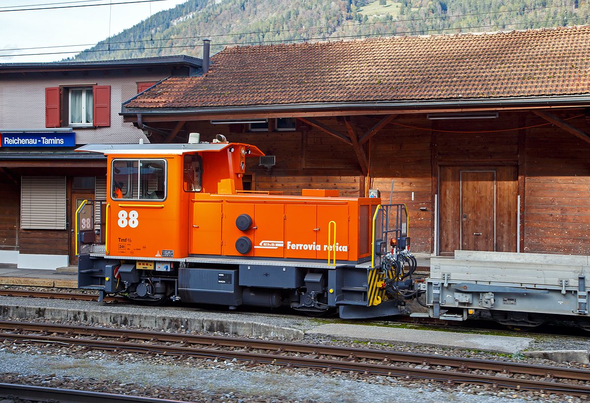 Äußerlich sieht er noch so aus wie der Alte, aber innerlich ist er komplett neu....
Der aus dem Refitrprogramm gekommene RhB Tmf 2/2 88 ist am 01.11.2019 im Bahnhof Reichenau-Tamins abgestellt, aufgenommen aus einem RhB Zug heraus.

Die Tmf 2/2  wurde 1992 von RACO (Robert Aebi AG, Regensdorf, Schweiz) unter der Fabriknummer 1989 gebaut und an die RhB geliefert. Die RACO Typenbezeichnung ist 420 CT 4H.Die Tmf 2/2 sind die mit Funkfernsteuerung ausgerüsteten Traktoren mit Verbrennungsmotoren der Rhätischen Bahn (RhB). Zwischen 1991 und 1994 wurden von RACO sechs dieser Tmf 2/2 mit den Nummern 85 bis 90 beschafft. Der Tmf 2/2 88 wurde nach dem Umbau in der RhB Werkstatt in Landquart Anfang Oktober 2018 erfolgreich durch das BAV abgenommen und durfte einige Tage später den Betrieb aufnehmen.

Die RhB Tmf 2/2 88 ist der Prototypenumbau, die im Rahmen des Projekts «Refit Baudienstfahrzeuge Tm(f) 2/2» werden die sechs Rangiertraktoren Tmf 2/2 85-90 mit den Baujahren1990 bis 1994, nach und nach, durch diverse Umbau- und Erneuerungsarbeiten fit für die Zukunft gemacht. Zu immer höheren Unterhalts- und Revisionskosten führen nach den Jahren im Betrieb einige Komponenten aus dem Antriebsstrang und dabei vor allem der Cummins-Dieselmotor. Aufgrund seines Alters kann dieser Motorentyp nicht mehr als Neuteil beschafft, sondern nur noch revidiert werden.

Aus diesem Grund hat sich die RhB vor einigen Jahren entschieden, diesen Dieselmotor bei den Tmf 2/2 85-90 zu ersetzen. Nach umfangreichen Untersuchungen wurde bald klar, dass nebst dem Dieselmotor auch einige andere zentrale Fahrzeugkomponenten von Obsoleszenz betroffen sind und weitestgehend nicht mehr den heutigen technischen Ansprüchen genügen. Dazu gehören Getriebe, Partikelfilteranlage, Kühlungsanlage, Hydraulik, Pneumatik, Bremsmechanik wie aber auch die komplette elektrische Einrichtung, die Fahrzeugsteuerung, die Sicherheitseinrichtung und die Fahrdatenvisualisierung. Grob umschrieben in etwa alles außer dem Chassis, Kabine und Achsen.

Antriebsstrang:
Aufgrund der betrieblichen Anforderungen entschied die RhB, den Reihen 6-Zylinder durch einen V8-Dieselmotor von Deutz zu ersetzen. Der neue Motor ist dank seiner V-Bauweise sehr kompakt und kann je nach Drehzahl bis zu 30 % mehr Leistung abgeben als der bestehende. Um diese Leistung optimal auf die Schienen zu bringen, wurde das bestehende Lastschaltgetriebe durch ein automatisches Wendegetriebe der Firma Voith ersetzt. Dieses Getriebe sowie auch die komplette Kühlanlage wurden von Voith auf die Leistungsdaten des Motors optimal abgestimmt. Ein großer Benefit nebst der Leistungssteigerung und der „Einfachheit“  des Antriebsstranges liegt darin, dass die Gangschaltung – mit welcher die restlichen Tmf  2/2 gestraft sind – nicht mehr von Relevanz ist. Dank dem neuen Automatikgetriebe lässt sich die Geschwindigkeit stufenlos und ohne Leistungseinbruch zwischen V null und V max einstellen.

Fahrzeugsteuerung und Fahrdatenvisualisierung
Die bestehende KraussMaffei-Fahrzeugsteuerung wurde durch eine von Selectron, die RhB-Standard ist, ersetzt. Die Antriebsstrangkomponenten (Dieselmotor / Getriebe) wie auch Fahrzeugkomponenten wie beispielsweise Display, Funkfernsteuerung usw. kommunizieren über einen Fahrzeugbus mit der Fahrzeugsteuerung. Dadurch erleichtert sich die Fehlerdiagnose und es konnten viele elektromechanische Komponenten eingespart werden. Die Fahrzeugdaten werden dem Lokführer über Displays visualisiert.

TECHNISCHE DATEN der RhB Tmf 2/2 88 (Refit):
Baujahre: 1991/92 und 1994
Spurweite: 1.000 mm (Meterspur)
Achsfolge: B
Länge über Puffer:  7.490 mm
Achsabstand: 3.750 mm
Breite: 2 700 mm
Eigengewicht:  24 t
Höchstgeschwindigkeit: 60 km/h (60 km/h Schleppfahrt)
Treibraddurchmesser: 	750 mm
Motorentyp: Deutz V8-Dieselmotor 
Weitere Daten wie auch Motor- und Getriebetyp sind mir leider noch unbekannt.
