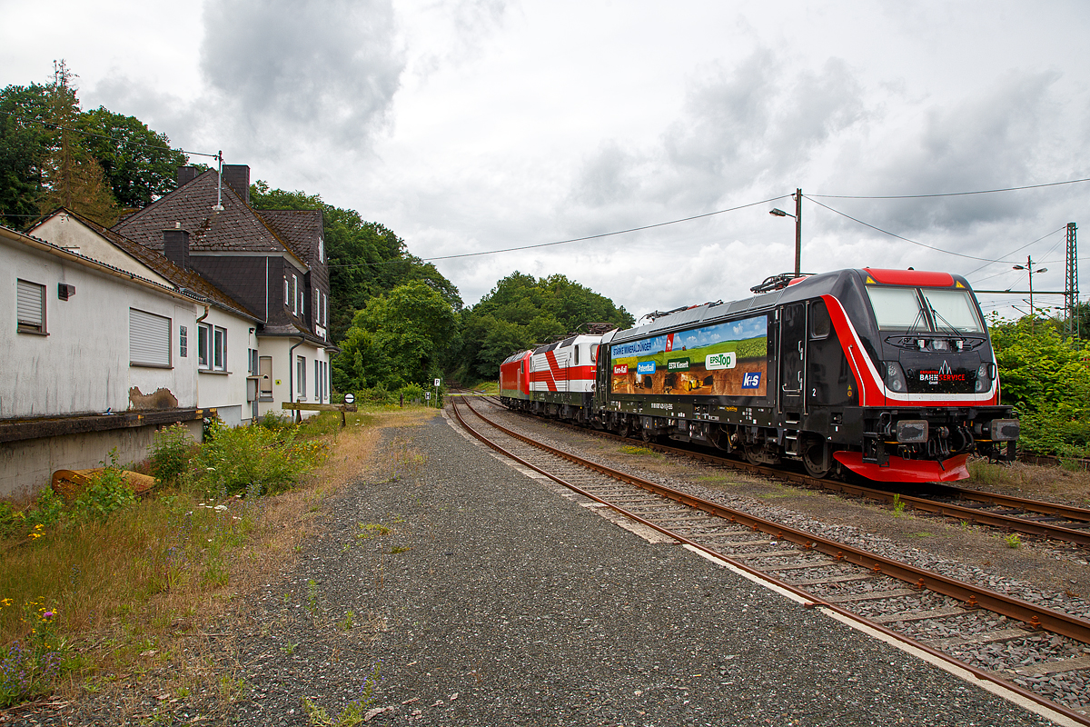 Am 05.07.2021 in Scheuerfeld (Sieg) beim Kleinbahnhof der WEBA (Westerwaldbahn) stehen bereit fr ihre nchste Aufgabe, der Abfuhr von schweren Holzzgen: 
Vorne die Bombardier TRAXX F160 AC3 LM, 187 420-5 (91 80 6187 420-5 D-EBS) der EBS _ Erfurter Bahnservice GmbH.
In der Mitte die  “Weie Lady” 143 822-5, alias 243 822-491 80 6143 822-5 D-EBS der EBS - Erfurter Bahnservice GmbH, ex RBH 139, ex DB 143 822-5. ex DR 243 822-4.
Und hinten die 156 002-8 (91 80 6156 002-8 D-FWK) der FWK - Fahrzeugwerk Karsdorf GmbH & Co. KG, ex MEG 802, ex DB 156 002-8, ex DR 252 002-1. 

Hier beim Kleinbahnhof der WEBA (Westerwaldbahn) in Scheuerfeld wird das Fichtenholz von den Holztransport-LKW´s  auf die Schiene verladen. Der komplette Fichtenbestand ist durch den Borkenkfer in der Region befallen und wird daher abgeholzt. Wer die Region kennt der ist erschreckt wie kahl teilweise die Hnge sind. Ein Glck das es hier nicht nur Fichten, sondern auch Laubwald gibt.