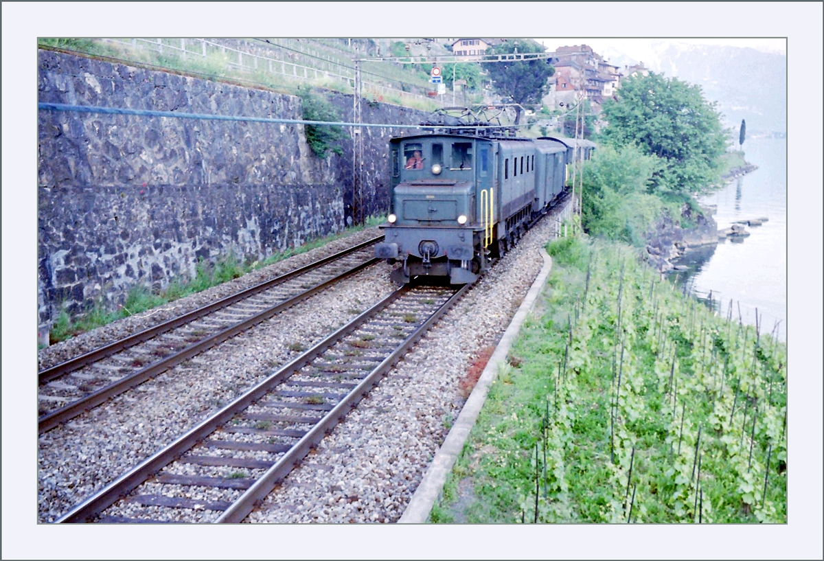 An etwa derselben Stelle zeigt sich eine Ae 4/7 mit einem Postzug auf dem Weg nach Vevey. 

Analogbild vom Mai 1995