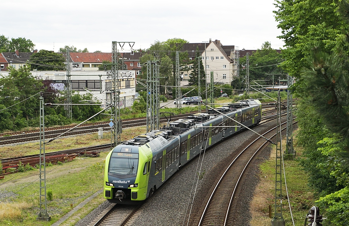Auf dem Weg von Hamburg-Altona nach Itzehoe hat der Flirt 3 der Nordbahn am 05.07.2023 den Bahnhof Elmshorn verlassen und befährt die ersten Meter der Marschbahn nach Westerland/Sylt. Die Fahrleitung endet aber bereits in Itzehoe. Im Hintergrund die Strecke nach Kiel/Flensburg.