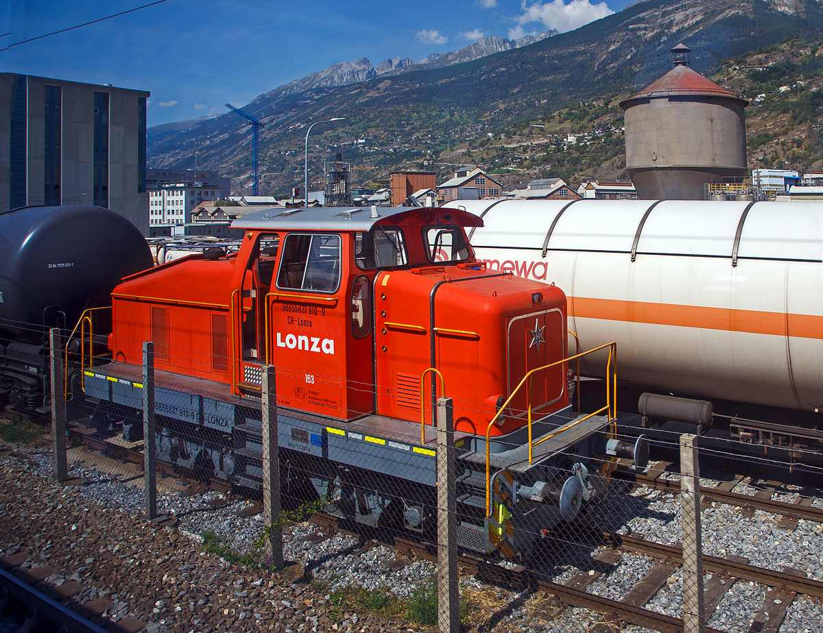 Aus dem Zug heraus, die Em 3/3 163  Rene  (98 85 5837 910-9 CH-LONZA) eine Henschel DHG 500 C der Lonza  AG (Visp), steht am 08.09.2021 in Visp.

Die Henschel  DHG 500 C wurde 1968 von Henschel in Kassel unter Fabriknummer  31239  gebaut und war erst als Mietlok im Einsatz. Im Jahr 1971 verkaufte sie dann Henschel an die Lonza AG in die Schweiz.
2014 wurde die Lok von der LSB Lok Service Balmer AG in Hinwil komplett neu revidiert und remotorisiert.

Die Henschel DHG 500 C ist eine dieselhydraulische Lokomotive, die von den Henschel-Werken gebaut wurde. Sie war vor allem fr den Einsatz im schweren Werksdienst vorgesehen. Die Lok gehrt zur ab 1962/63 angebotenen sogenannten vierten Generation der Henschel-Loks, der ersten Generation mit Gelenkwellenantrieb. Die Aufbauten wurden dabei ohne groe nderungen von der vorigen Generation bernommen.  Zur besseren Bogenlufigkeit war die mittlere Achse seitenverschiebbar gelagert. 

Von den Henschel DHG 500 C wurde zwischen 1963 und 1976 insgesamt  62 Exemplaren gebaut. Die Loks gingen vornehmlich an Bergbaugesellschaften und Stahlproduzenten sowie Chemieunternehmen. So erwarb die Rheinelbe Bergbau AG in Gelsenkirchen elf Loks und die Hibernia AG, Zechenbahn- und Hafenbetriebe Ruhr-Mitte in Gladbeck neun Loks vom Typ DHG 500 C. Die meisten Lokomotiven wiesen bei Auslieferung den Henschel-Standardanstrich in Blau mit zwei horizontalen Zierstreifen an den Vorbauten auf. Die durch Zusammenschluss entstandene Ruhrkohle AG hatte zeitweise 31 Lokomotiven dieses Typs im Bestand. 

TECHNISCHE DATEN (nach Umbau):
Spurweite: 	1.435 mm (Normalspur)
Achsformel: C
Lnge ber Puffer:  9.900 mm
Hhe:  4.225 mm
Breite: 3.040 mm
Fester Radstand:  3.700 mm
Kleinster bef. Halbmesser: 	80 m
Dienstgewicht:  60 t
Hchstgeschwindigkeit: 30 km/h / 60 km/h (Schleppfahrt 70 km/h)
Treibraddurchmesser: 	1.000 mm
Motor:  neuer Deutz V6 Motor mit elastischer Vorschaltkupplung. inkl. Partikelfilter (Vollstrombrenner mit aktiver Regeneration), 
der ehemalige Motor war ein Henschel 12V 1416 
Installierte Leistung:  368 kW (500 PS)
Getriebe: Voith
Leistungsbertragung: hydraulisch (ber Gelenkwellen)
