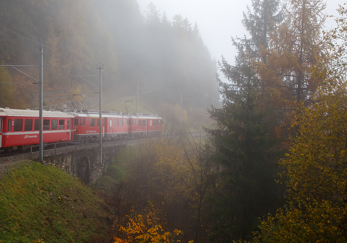 Bei Nebel.....
Geführt von den beiden RhB ABe 4/4 III Triebwagen Nr. 54  Hakone  und 53  Tirano  fährt am 02.11.2019 unser RhB Regionalzug nach Tirano, nun von Cavaglia weiter hinab in Richtung Poschiavo. Hier überquert der Zug den 10 m langen Lehnenviadukt.