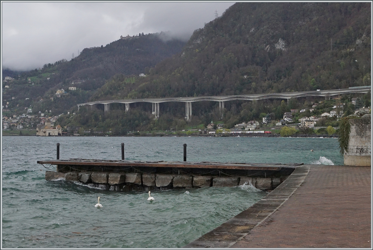Beim Blick über den aufgewühlten Genfersee ist weit im Hintergrund recht des Château de Chillon eine SBB Re 460 mit ihrem IR90 auf der Fahrt nach Brig zu entdecken. 

1. April 2024