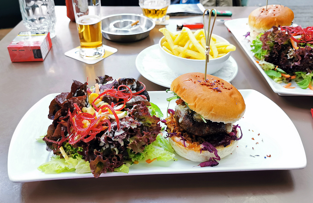  Burger Postplatz   am 05.09.2021 in Chur. Saftiger CH-Burger mit Speck, Rucola, Kabis & Bergkäse an leicht pikanter Haussauce, dazu bunter Salat. 