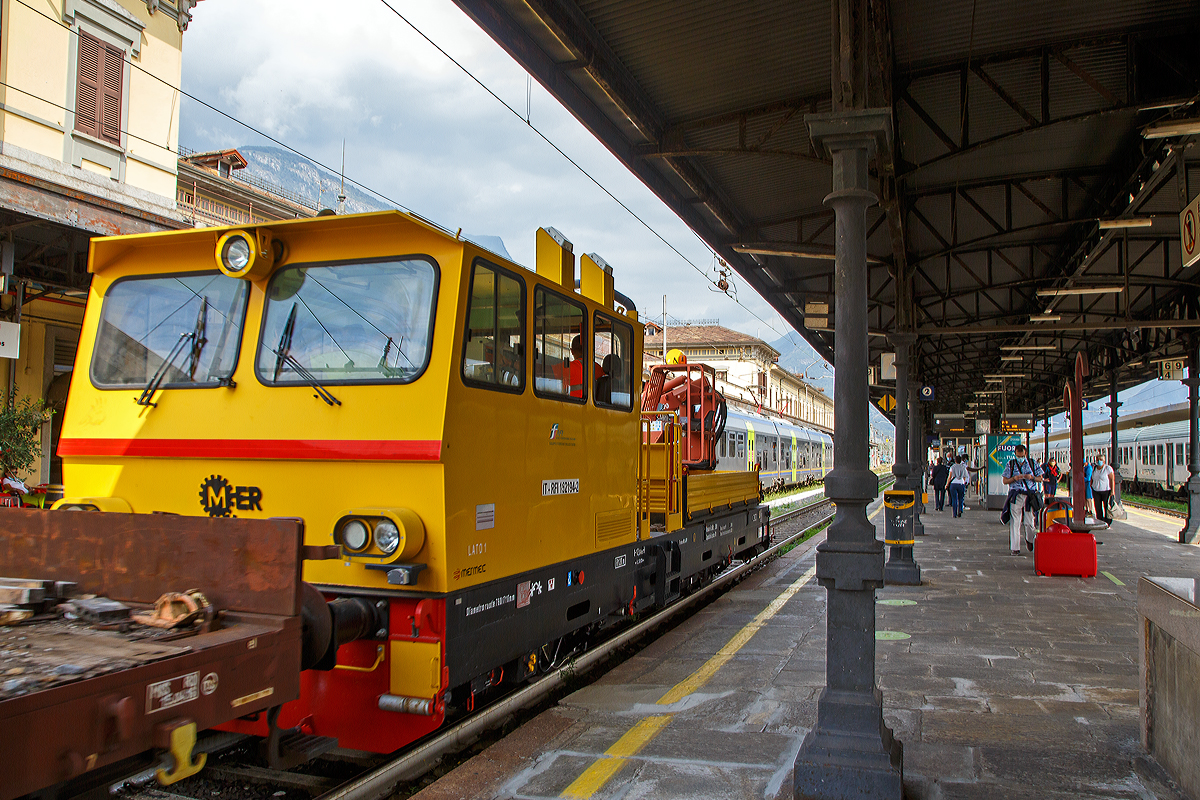 Das Italienische MerMec Gleisarbeitsfahrzeug IT-RFI 152 194-2 der RFI (Rete Ferroviaria Italiana) fährt am 08.09.2021 mit einem vierachsigen Flachwagen durch den Bahnhof Domodossola in Richtung Norden.