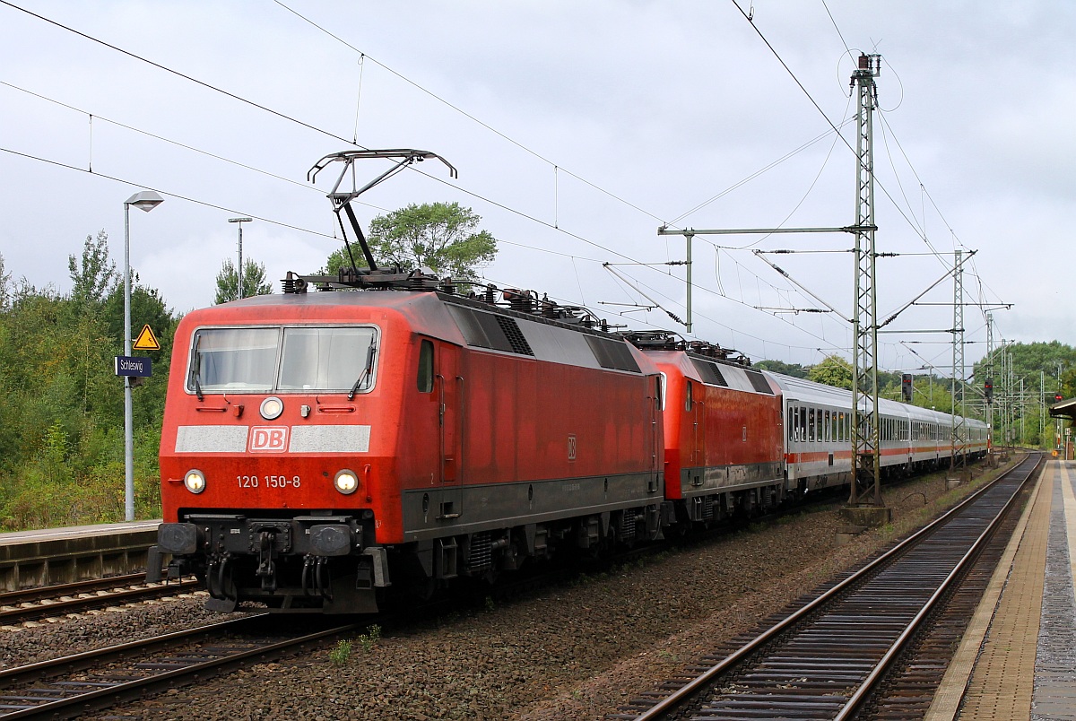 DB 120 150-8 hat hier die wohl defekte 120 154-0 mit dem Wagenpark des IC 1970 am Haken und fährt mit hohem Tempo durch Schleswig. 03.09.2013