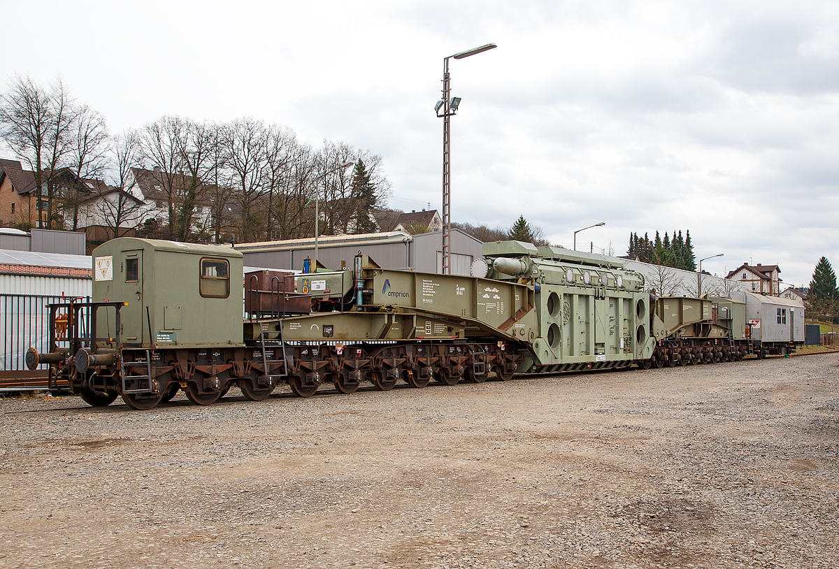 
Der 20-achsiger Tragschnabelwagen der Gattung Uaai 687.9 (84 80 996 0 003-5 D-AMPR) der Amprion GmbH beladen mit einem 150 000 kVA Wandertransformator (Trafo 211) der Trafo-Union (heute Siemens) abgestellt, mit dem Begleitwagen zum Tragschnabelwagen (60 80 092 3 040-0 D-AMPR), am 17.03.2017 in Kreuztal. 

Die Amprion GmbH ist ein deutscher Übertragungsnetzbetreiber für den Strombereich. Das Unternehmen, welches als Teil des RWE-Konzerns entstand, beschäftigt etwa 1100 Mitarbeiter, sein Hauptsitz befindet sich in Dortmund.

Der Tragschnabelwagen wurde 1961 bei MAN unter der Fabriknummer 146523 gebaut. Es wurden 3 Stück der Bauart Uaai 687.9 hergestellt.

TECHNISCHE DATEN:
Spurweite: 1.435 mm (Normalspur)
Anzahl der Achsen: 20 in 4 Drehgestellen á 5 Achsen
Gattung/Bauart: Uaai 687.9
Länge über Puffer: 32.070 mm (Leerfahrt) / 41.140 mm (mit Trafo)
Drehzapfenabstand 1: 15.886 mm (Leerfahrt) / 24.956 mm (mit Trafo)
Drehzapfenabstand 2 (zw. den DG1+2 / DG 3+4): 7.500 mm
Achsabstand in den Drehgestellen: 1.500 mm
Laufraddurchmesser: 1.000 mm
Eigengewicht: 117 t
Maximale Ladegewicht: 250 t
Achsdruck: 5,85 t (Leerfahrt) / 18,35 t (mit Trafo)
Meterlast: 3,65 t/m (Leerfahrt) / 8,92 t/m (mit Trafo)
Höchstgeschwindigkeit: 90 km/h (Leerfahrt) / 40 km/h (Beladen)
Kleinster befahrbarer Gleisbogenhalbmesser: 75 m
Tragende Bauteile gefertigt aus: MSt 52-3
Bauart der Handbremse: bodenbedienbare Handbremse 2 x 45 t