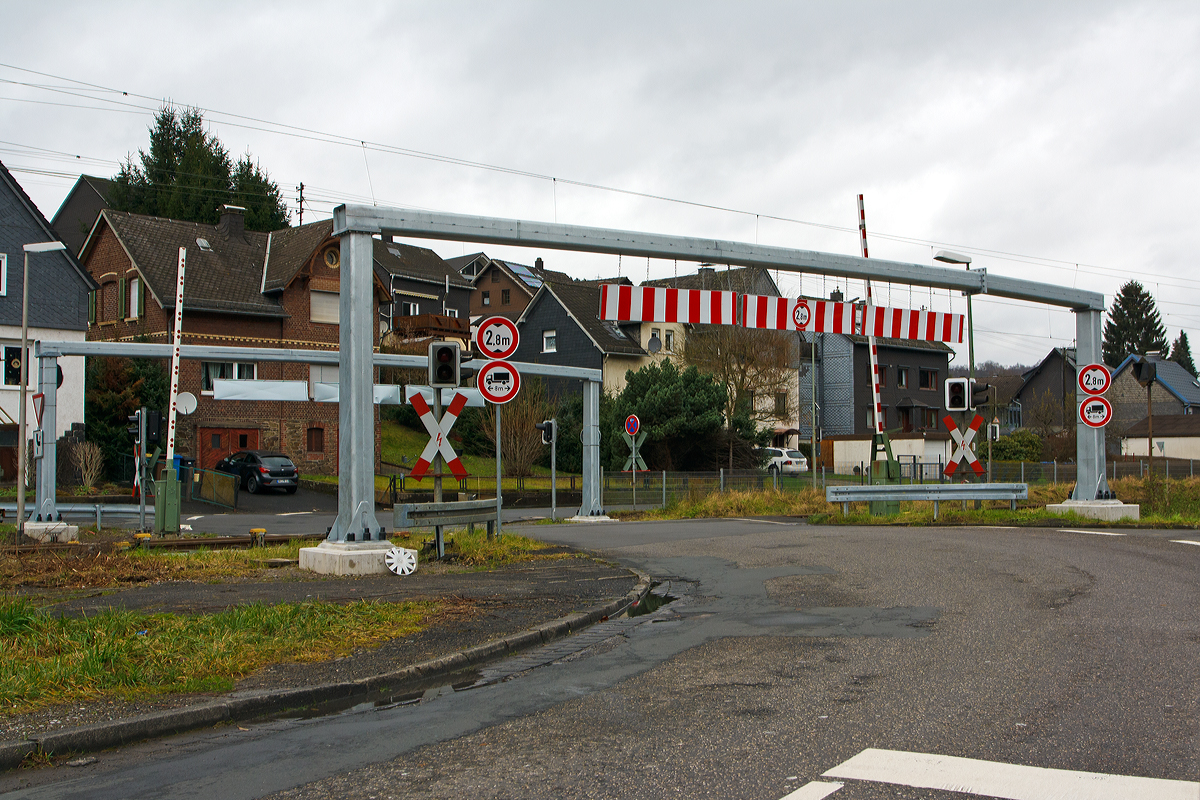 
Der Bahnübergang  in Mudersbach an der Siegstecke, KBS 460  (Bü km 114,7) am 21.12.2014. 

Seit Mai 2014 gibt es die Hindernisse für größere LKW vor jeder Seite, da Verbotsschilder nicht ausreichten (bzw. manche die Abmessungen ihres Fahrzeuges nicht kennen. 

Wie man sieht geht es stumpf um die Ecke (die gegenüber liegende Straße geht parallel zur Bahnstrecke weiter) und da hat sich schon mancher LKW verkeilt d.h. kam nur durch mehrmaliges Rangieren weiter. So kam es hier schon mehrfach zu Unfällen mit dem Zugverkehr, die Schranke schloss aber es hing noch ein LKW fest. Am 26. November 2013 hatte sich z.B. ein Sattelzug sich am Bahnübergang festgefahren und der Regionalexpress RE 9 war in ihn gefahren, zum Glück ohne größere Katastrophe. Drei Personen wurden dabei leicht verletzt, neben dem Zugführer und einem Fahrgast auch ein Passant, der sich in der Nähe aufhielt.
