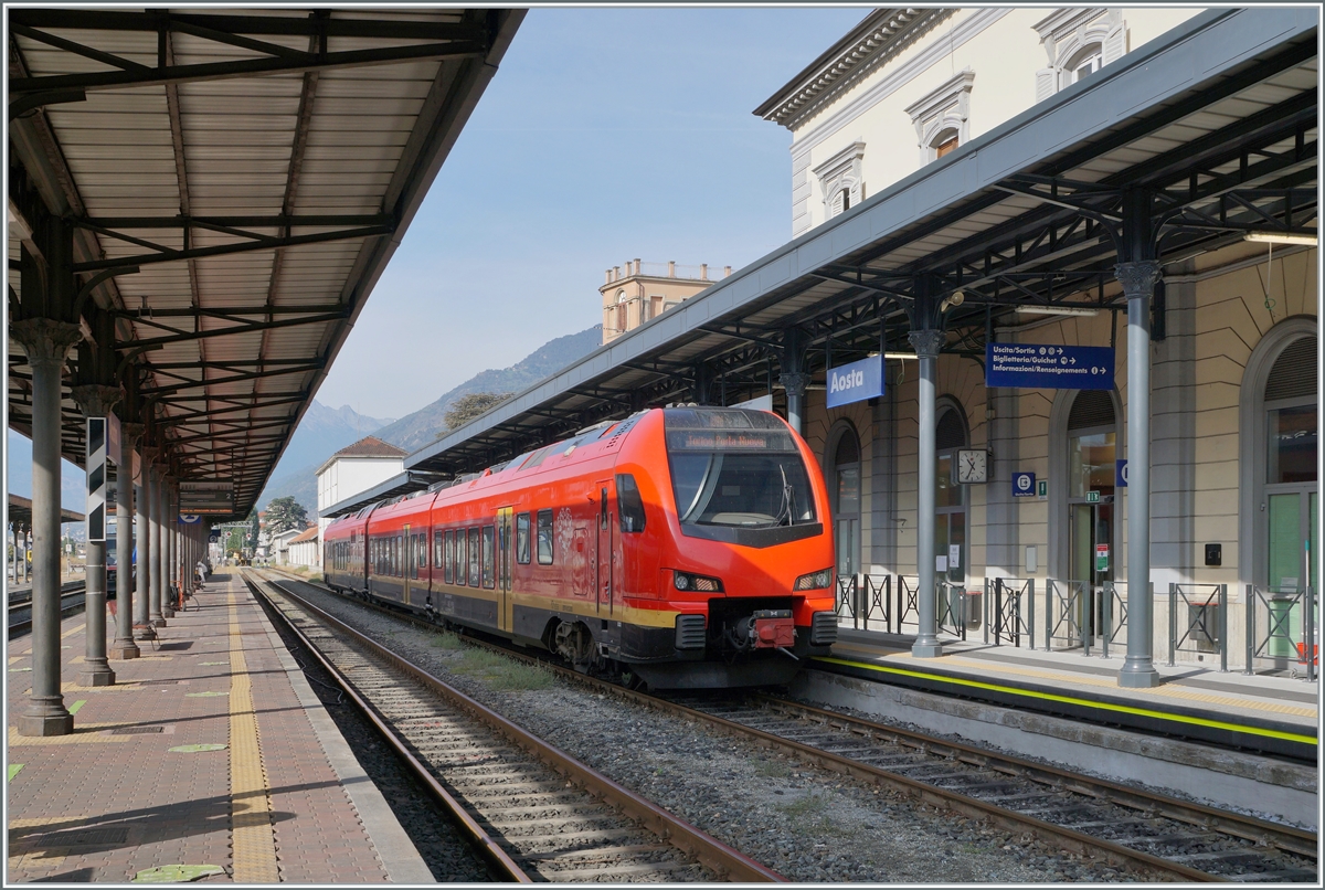 Der bimodale FS Trenitalia BUM BTR 831 003 wartet als Regionale 2722 in Aosta mit dem Ziel Torino Porta Nuova auf die baldige Abfahrt. Der Zug kann mit Dieselmotoren oder elektrisch mit 3000 Volt Gleichstrom betreiben werden, verfügt für die Achsanordnung Bo' 2'2'2' Bo' und die UIC Bezeichnung (des Antriebsmodul) lautet 90 83 1831 012-1 I-TI. 

27. September 2021