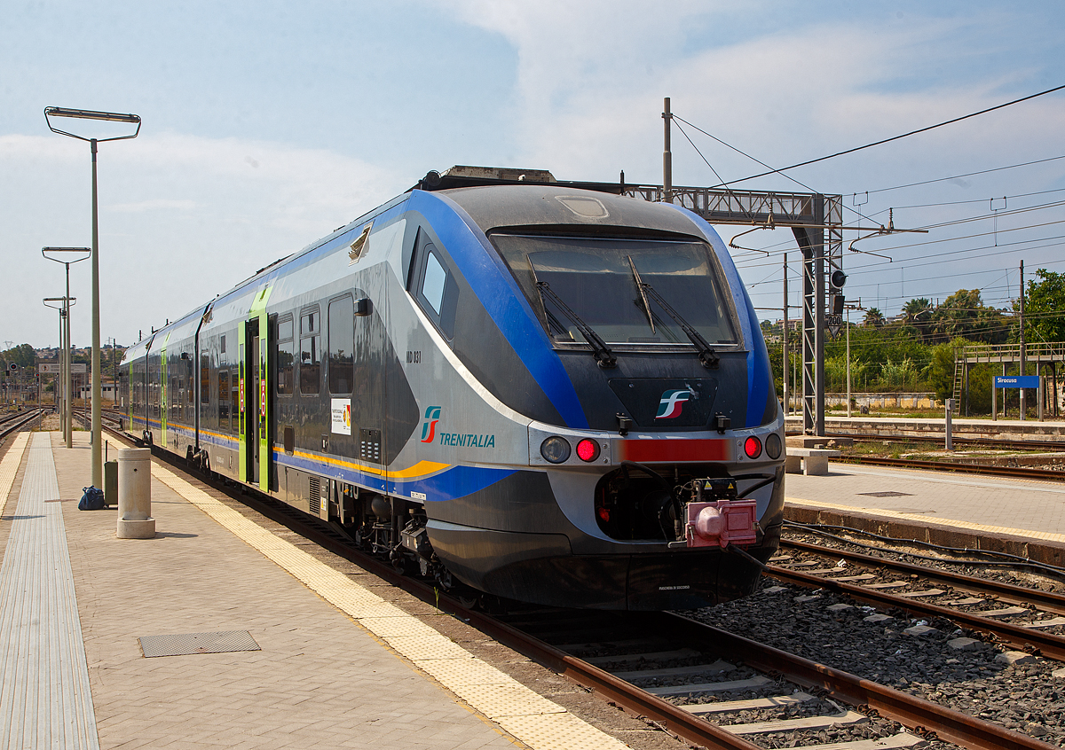 Der dreiteilige Minuetto Diesel MD 031 der Trenitalia steht am 19.07.2022 im Bahnhof Syrakus (Stazione di Siracusa), als Regionalzug R 12938 nach Vittoria, zur Abfahrt bereit. Er fhrt via Fontane Bianche, Avola, Noto, Pozzallo, Sampieri, Ragusa, Donnafugata und Comiso, so fhrt er auch an den sdlichen Zipfel von Sizilien.

Diese dreiteiligen Diesetriebzge der italienischen Baureihe ALn 501 / Ln 220 / ALn 502 (MD - Minuetto Diesel) sind die Diesel Variante der Alstom-Coradia-Meridian-Familie, hnlich wie die ME - Minuetto Elettrico (ALe 501 / Le 220 / ALe 502). Die italienischen Minuetto MD und ME sind die Mutter der Produktfamilie der Alstom Coradia Meridian, von diesen wurden spter auch Triebzge fr Deutschland und Nordeuropa abgeleitet. 

Von dieser Diesel Variante ALn501 / Ln220 / ALn 502 (MD) wurden 114 Stck, zwischen 2003 und 2009, von Alstom Ferroviaria S.p.A. (ex Fiat Ferroviaria) in Italien gebaut. Von der elektrischen Variante ALe 501 / Le 220 / ALe 502 (ME) wurden 136 Stck zwischen 2003 und 2010 gebaut. Beide Varianten sind als dreiteilige Triebzge ausgefhrt. Der Minuetto ist komfortabler klimatisierter Triebwagenzug der auf dem Alstom Coradia Meridian basiert. 

Er wurde von Giorgetto Giugiaro entworfen und wurde speziell fr den italienischen Markt entwickelt. Gebaut wurden sie in Italien von Alstom Ferroviaria in den italienischen Produktionsstandorten. Die Endmontage und Gesamtprojektmanagement geschah im ehemaligen Fiat Ferroviaria Werk in Savigliano. Die Drehgestelle kommen aus dem Alstom Werk Salzgitter in Deutschland.

Wie auch die anderen Zge der Coradia-Plattform, sind die Wageneinheiten fest miteinander verbunden und knnen nur in auergewhnlichen Wartungs- oder Pannenfllen getrennt werden. Ein Triebzug ist durchgngig niederflurig und barrierefrei.

Die Antriebskpfe ruhen jeweils auf einem Triebdrehgestell (konventionelle Enddrehgestelle) und sttzen sich zum anderen auf einer Hlfte eines Jakobs-Drehgestelles ab. Der Mittelwagen ruht beidseitig jeweils auf einer Hlfte eines Jakobs-Drehgestelles. Die Triebzge sind Scharfenberg-Kupplungen ausgestattet, mit der bis zu drei Zge in einem Zug verbunden werden knnen. Ein Dieseltriebzug kostet rund 3,45 Millionen Euro pro Fahrzeug, 150.000 Euro mehr als die Elektro-Version.

Die beinahe 52 m langen Fahrzeuge bieten 23 Sitzpltze in der 1. Klasse und 98 Sitzpltze in der 2. Klasse an. Der Antrieb erfolgt auf die beiden Enddrehgestelle, whrend die beiden Jakobs-Drehgestelle ohne Antrieb sind. Jedes Triebdrehgestell wird von im Unterflur eingebauten gedrosselten IVECO-V8-Dieselmotor mit Common-Rail-Direkteinspritzung, vom Typ IVECO V8 FVQE 28 angetrieben. Die Kraftbertragung vom Motor aufs Drehgestell geschieht hydraulisch, durch ein hydromechanisches Getriebe mit hydrodynamischer Bremse vom Typ Voith T 212 bre.

TECHNISCHE DATEN der MD - Minuetto Diesel:
Spurweite:  1.435 mm (Normalspur)
Achsformel:  Bo' 2' 2' Bo'
Lnge ber Puffer:  51.900 mm
Drehzapfenabstand: 14.650 mm / 13.650 mm /14.650 mm
Achsabstand im Trieb-Drehgestell:  2.400 mm
Achsabstand im Lauf-Drehgestell:  2.700 mm
Treibraddurchmesser:  850 mm
Breite. 2.950 mm
Hhe:  3.820 mm
Eigengewicht:  100 t
Hchstgeschwindigkeit:  130 km/h
Motoren: 2 Stck V8-Dieselmotor mit Common-Rail-Direkteinspritzung, Typ Iveco V8 FVQE 28
Getriebe: Voith T 212 bre (hydromechanisch mit hydrodynamischer Bremse)
Leistungsbertragung: hydraulisch
Nennleistung (gedrosselt): 2 x 560 kW (760 PS) bei 2.100 U/min
Leistung ungedrosselt: 2 x 720 kW (980 PS)
Sitzpltze:  23 in der 1. Klasse und 98 in der 2 Klasse
Kupplung: Scharfenberg