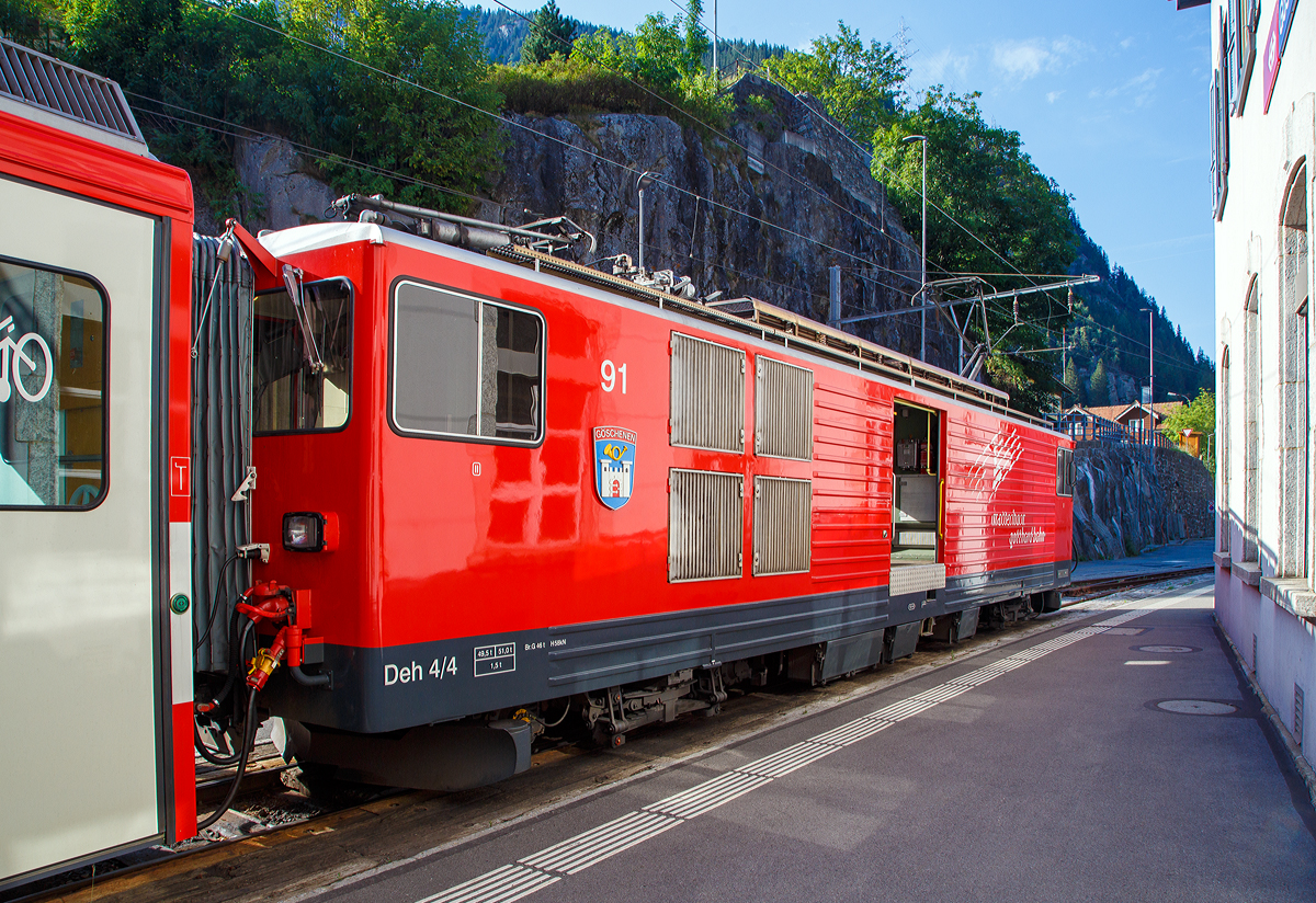 
Der Elektrische Zahnradgepäcktriebwagen MGB Deh 4 /4 II – 91 „Göschenen“, ex FO Deh 4/4 II – 91, steht am 01.08.2019 mit ihrem Schöllenenbahn Regionalzug nach Andermatt, im Bahnhof Göschenen zur Abfahrt bereit.

Der Gepäcktriebwagen wurde 1979 von SLM (mechanischer Teil, Lokomotivkasten) und BBC (elektrische Ausrüstung) gebaut.

Der Deh 4/4 II ist ein schmalspuriger Gepäcktriebwagen der Matterhorn-Gotthard-Bahn (MGB) für Adhäsions- und Zahnradbetrieb.

Weil die Furka-Oberalp-Bahn (FO) mit den Deh 4/4 I gute Erfahrungen gemacht hatte, beschaffte sie die Deh 4/4 II als Nachfolger. Im Zuge des Zusammenschlusses der FO mit der BVZ kamen sie zur neuen Gesellschaft Matterhorn-Gotthard-Bahn, wo sie nur noch als Deh 4/4 bezeichnet und, wenn nötig, anhand der Seriennummern 2.., 5.. und 9.. unterschieden werden.

Technische Daten:
Spurweite: 1.000 mm
Achsformel: Bo’Bo’
Länge über Puffer: 15.500 mm
Drehzapfenabstand: 8.800 mm
Achsabstand im Drehgestell: 2.790 mm
Größte Breite: 2.683 mm
Größte Höhe (bei abgesenkten Stromabnehmer): 3.880 mm
Leergewicht: 49,5 t (davon Mechanischer Teil 28 ,5 t)
Dienstgewicht: 51,0 t
Maximale Zuladung: 1,5 t
Gepäckraum Fläche: 10 m²
Höchstgeschwindigkeit: Adhäsion 60 km/h / Zahnstange 30 km/h
Stundenleistung: 1.032 kW
Dauerleistung: 936 kW
Stundenzugkraft am Rad: 117,2 kN
Dauerzugkraft am Rad: 101,2 kN
Maximale Zugkraft am Rad: 247,2 kN
Stromsystem: 11 kV 16,7 Hz AC
Anzahl der Fahrmotoren: 4
