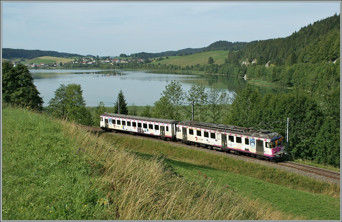 Der ex MThB ABDe 4/4 (538 316-1) mit seinem Bt zeigt sich leider etwas zu üppig mit Werbung beklebt in der sonst so entspannten Juralandschaft des Vallée des Joux bei Le Pont. 
16. Aug. 2009