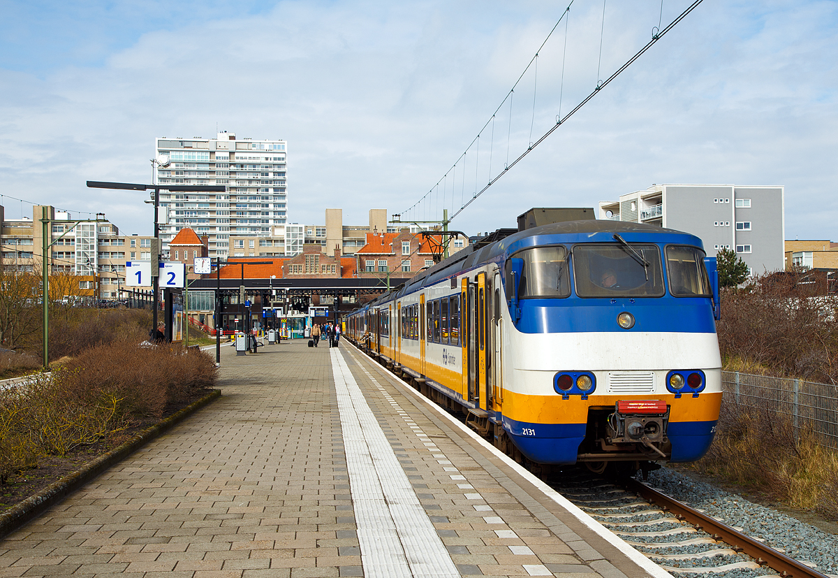 
Der kleine aber sehr schmucke Bahnhof Zandvoort aan Zee von der Gleiseite am 31.03.2018. Der Bahnhof ist ein zweigleisiger Kopfbahnhof. 

Auf Gleis 2 (Spoor 2) steht der Sprinter nach Amsterdam Centraal zur Abfahrt gerade bereit. Der Sprinter besteht aus einem zweitiligen Plan Y (Mat '74) 2131 (Series 2100) gekuppelt mit dem dreiteiligen Plan Y (Mat '74) 2967 (Series 2900). 

Diese 120 km/h schnellen Elektrischen Schnelltriebwagen wurden ab 1975 von der Waggonfabrik Talbot in Aachen für die Nederlandse Spoorwegen (NS) gebaut. 